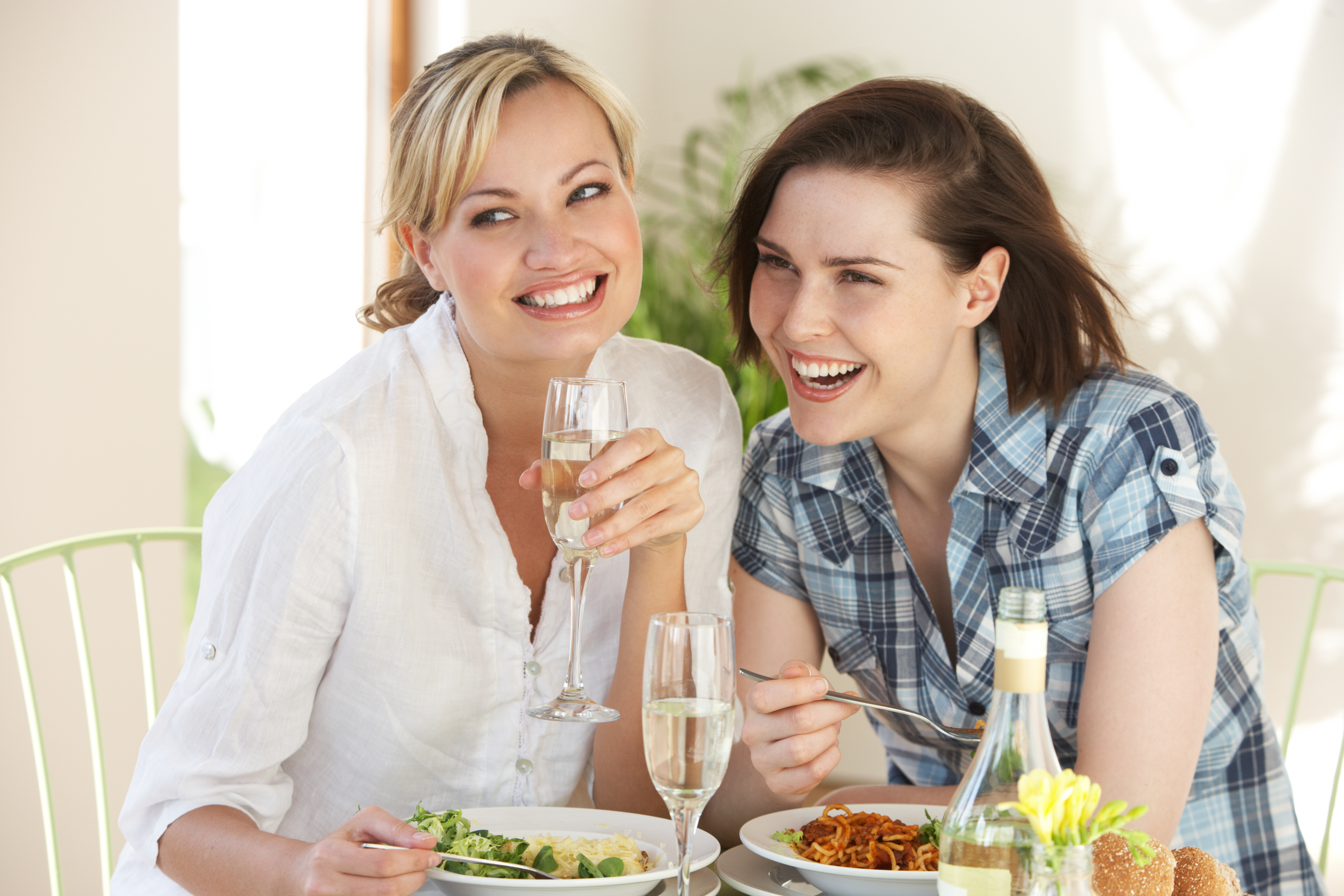 Deux femmes heureuses partageant des boissons et un repas | Source : Getty Images