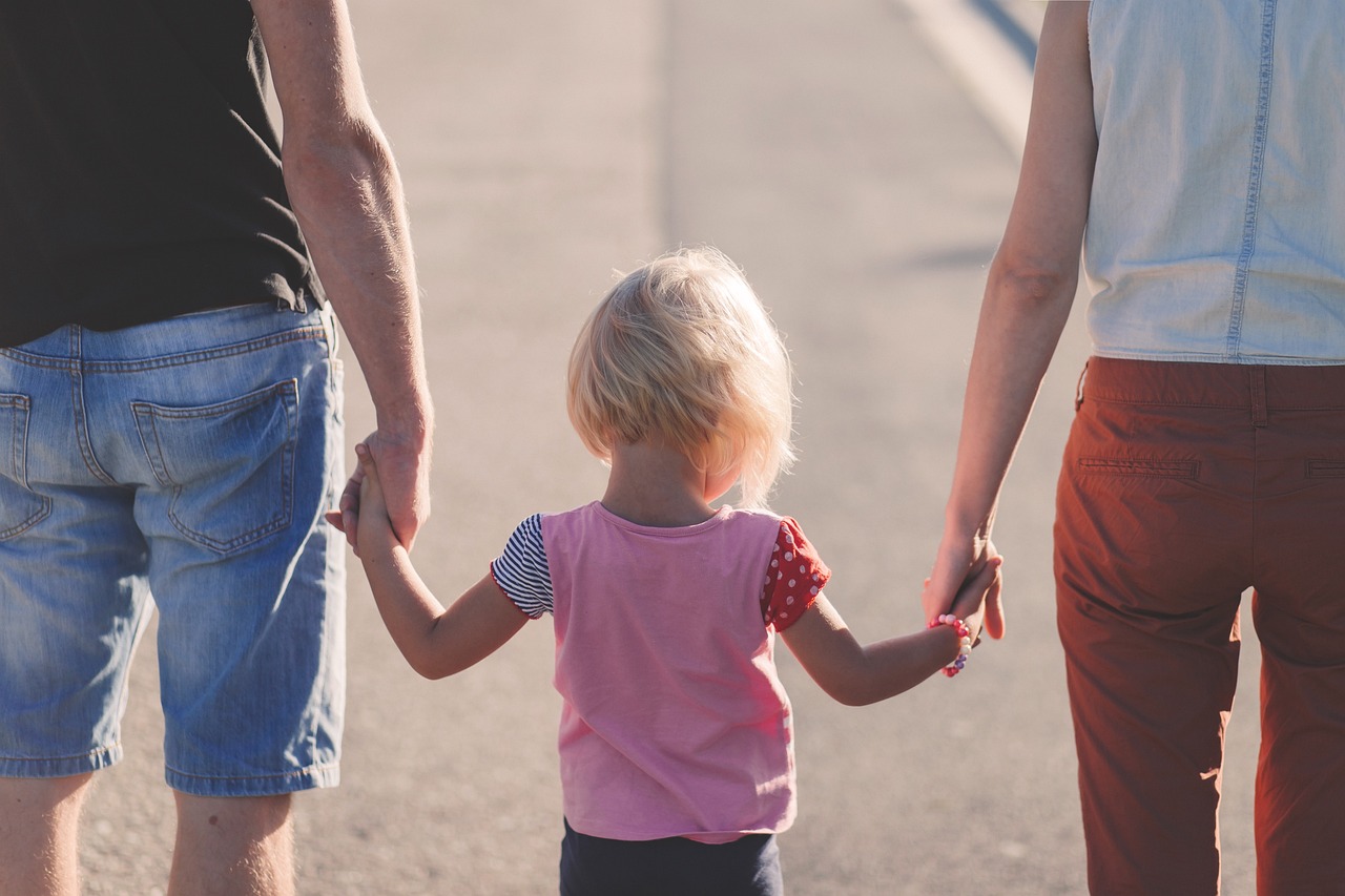 Des parents tenant les mains de leur fille | Source : Pixabay