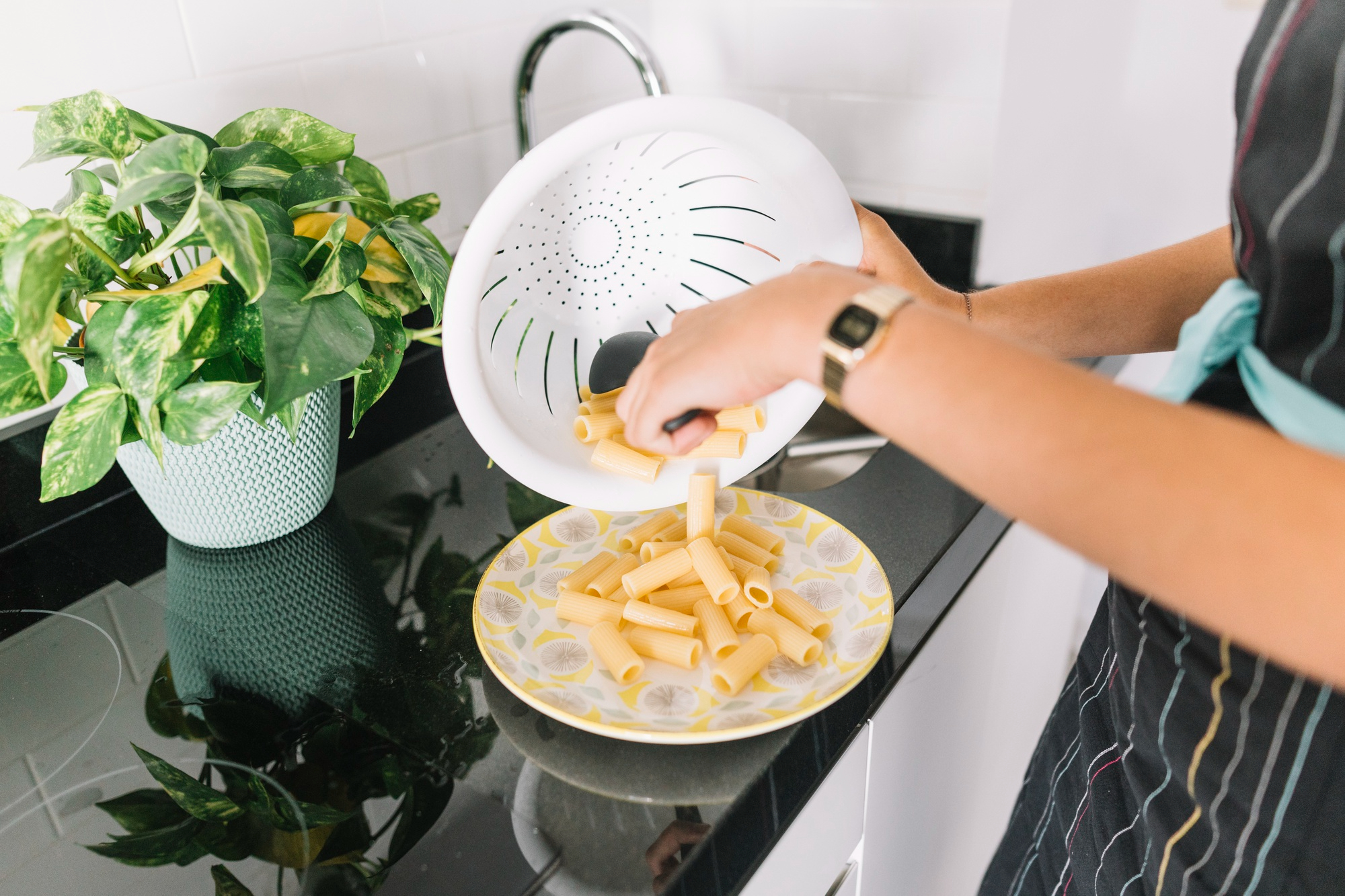 Une femme qui verse des pâtes cuites dans une assiette | Source : Freepik