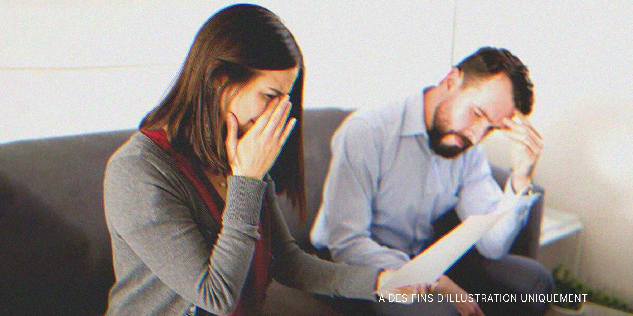 Une femme pleurant en tenant un morceau de papier dans sa main avec un homme assis à côté d'elle | Source : Shutterstock