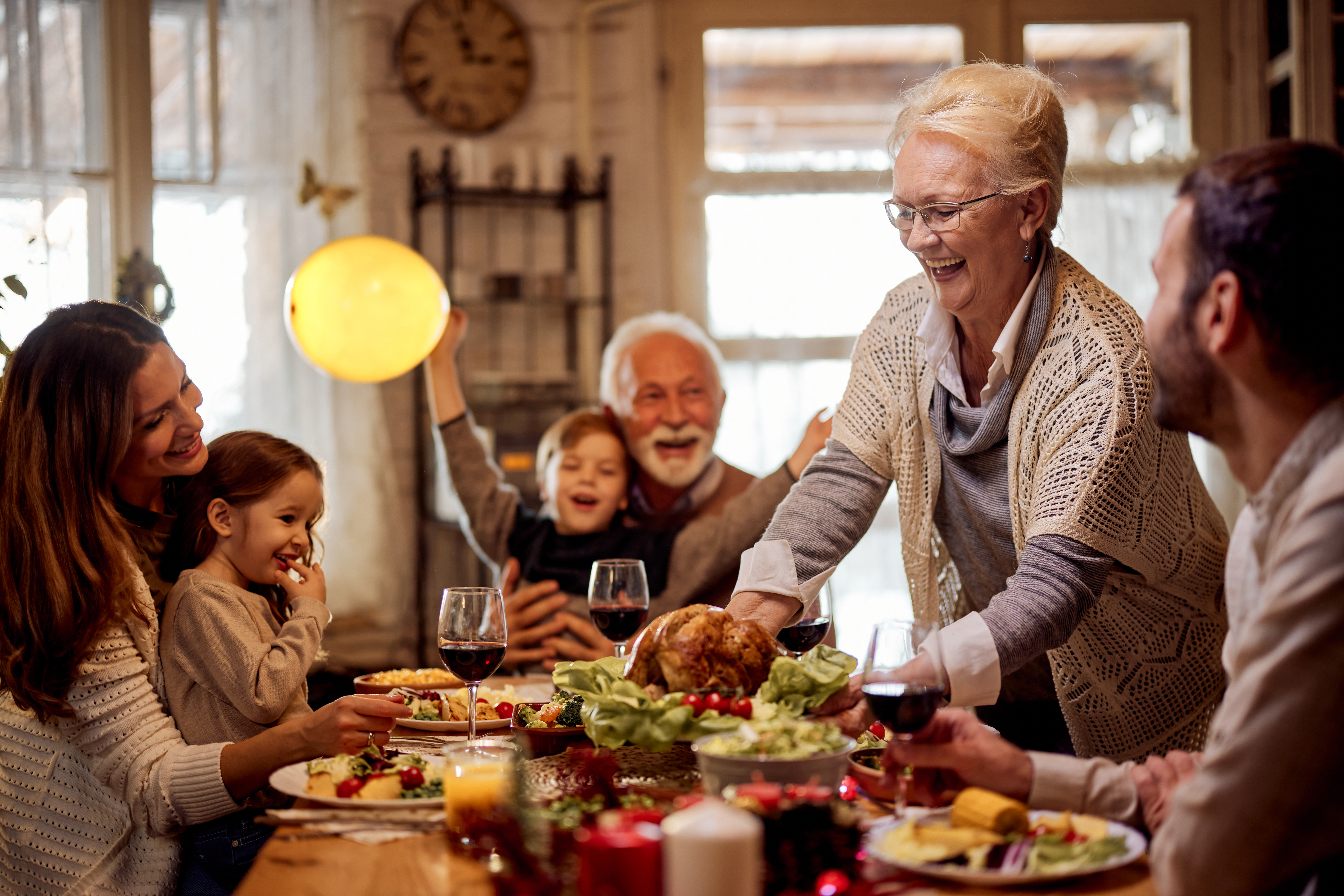 Une femme âgée heureuse sert un repas à sa famille dans la salle à manger | Source : Getty Images