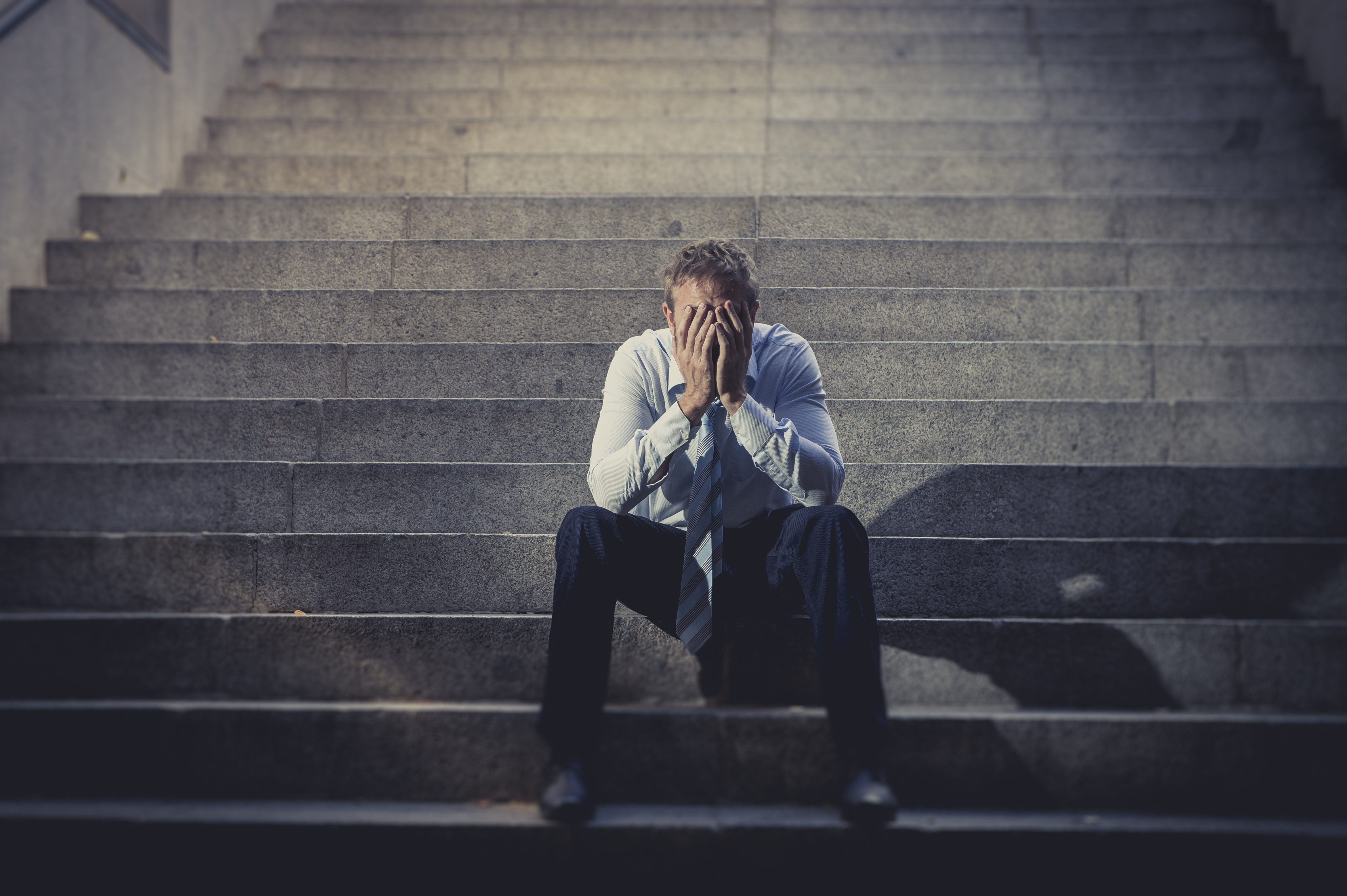 Un homme déprimé assis sur des escaliers en béton | Source : Shutterstock