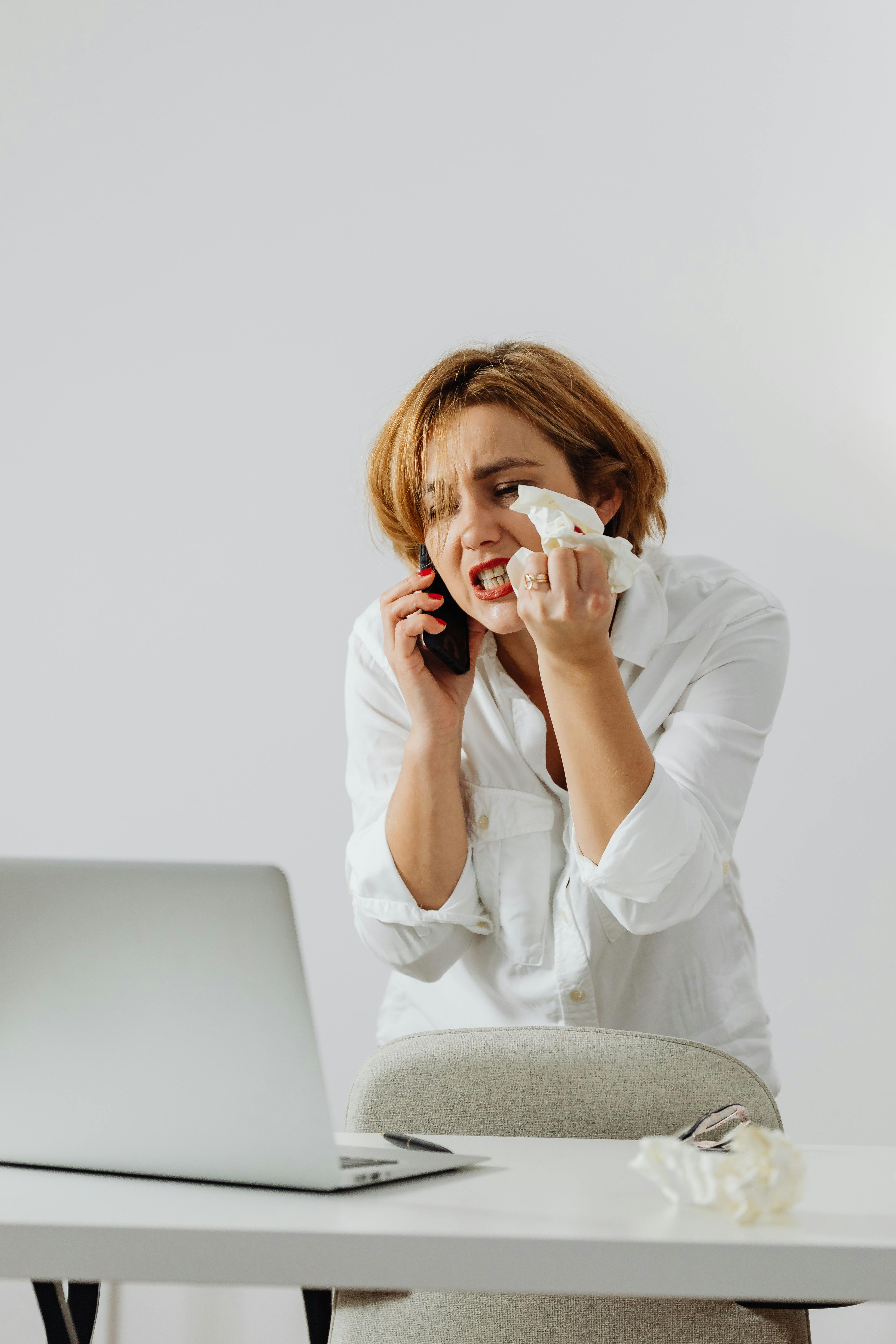 Une femme contrariée froisse un mouchoir en papier alors qu'elle est au téléphone | Source : Pexels