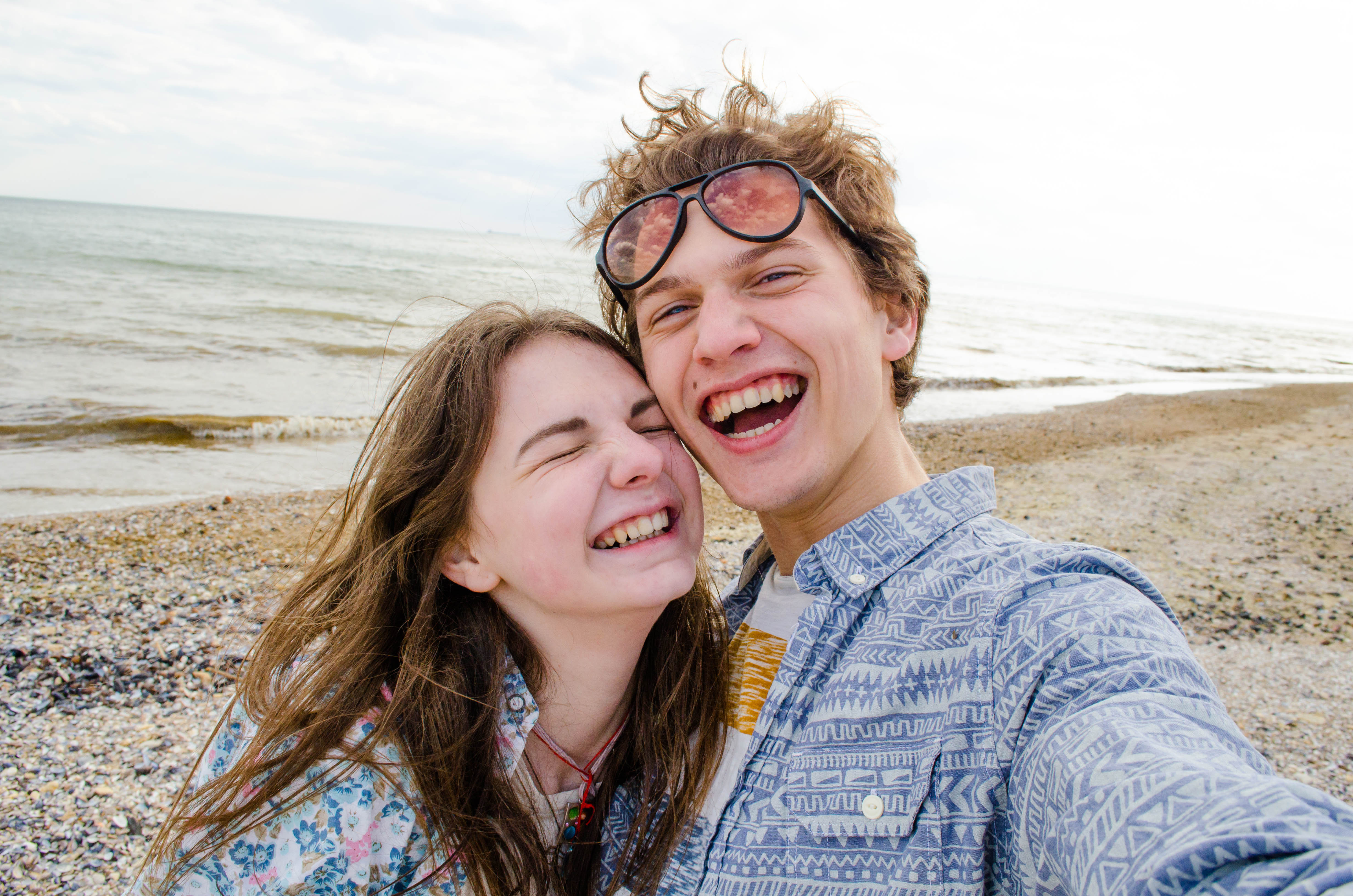 Un jeune couple prenant un selfie sur la plage | Source : Shutterstock
