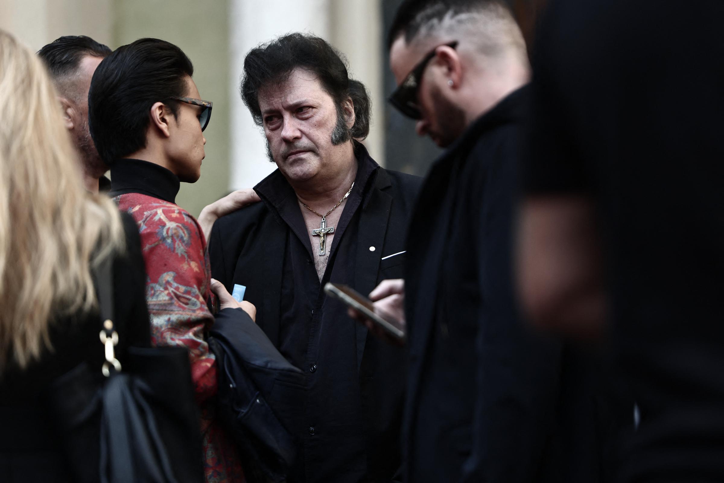 Le chanteur et imitateur d'Elvis Presley Eryl Prayer (au centre à droite) écoute le mannequin français Jérémy Bellet (à gauche) alors qu'ils quittent la cathédrale Sainte-Réparate de Nice, dans le sud-est de la France, après avoir assisté aux funérailles de Loana Petrucciani, première star de la télé-réalité en France, retrouvée morte à son domicile à l'âge de 48 ans, le 10 avril 2026 I Source : Getty Images