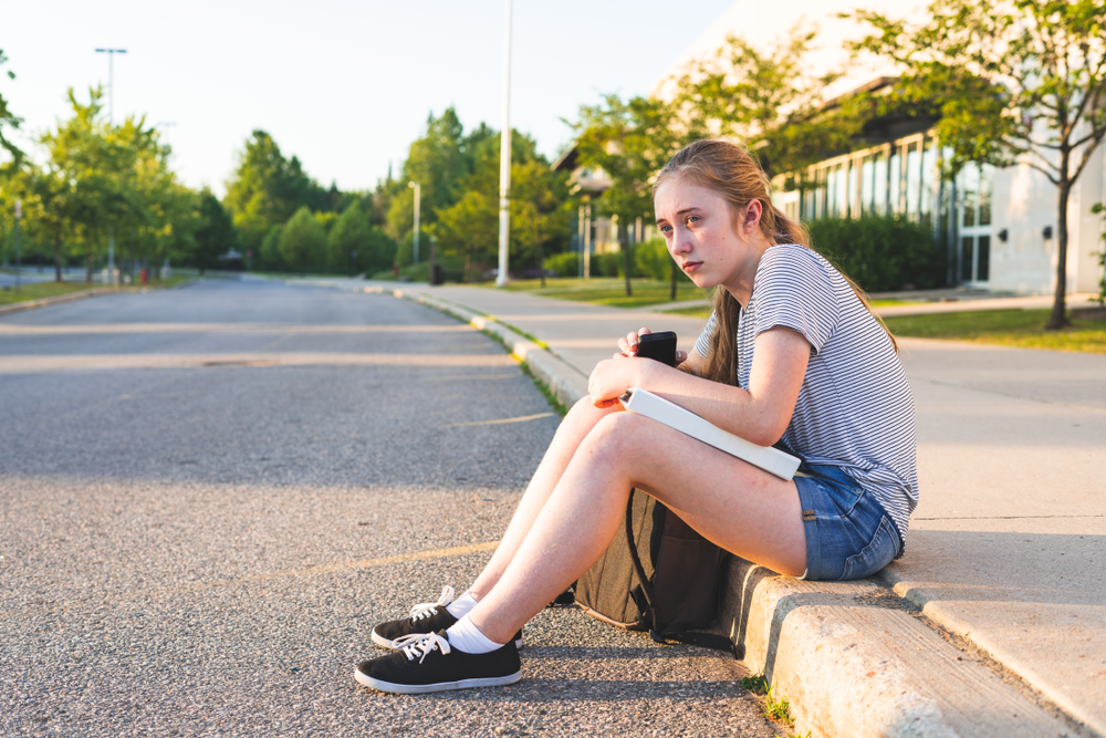 Une jeune fille assise au bord d'une route | Source : Shutterstock