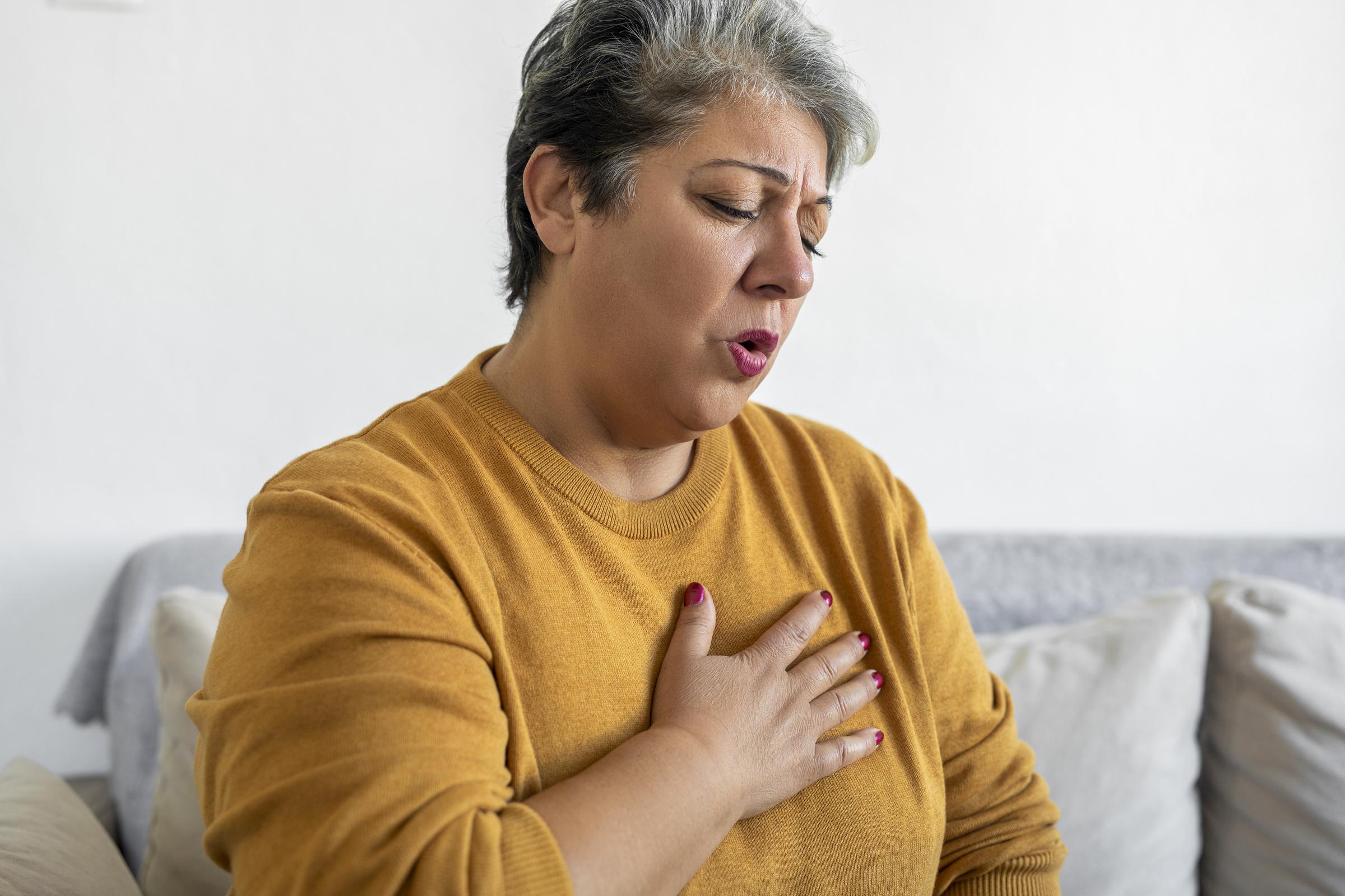 Femme se serrant la poitrine, ressentant des douleurs et des difficultés à respirer | Source : Getty Images