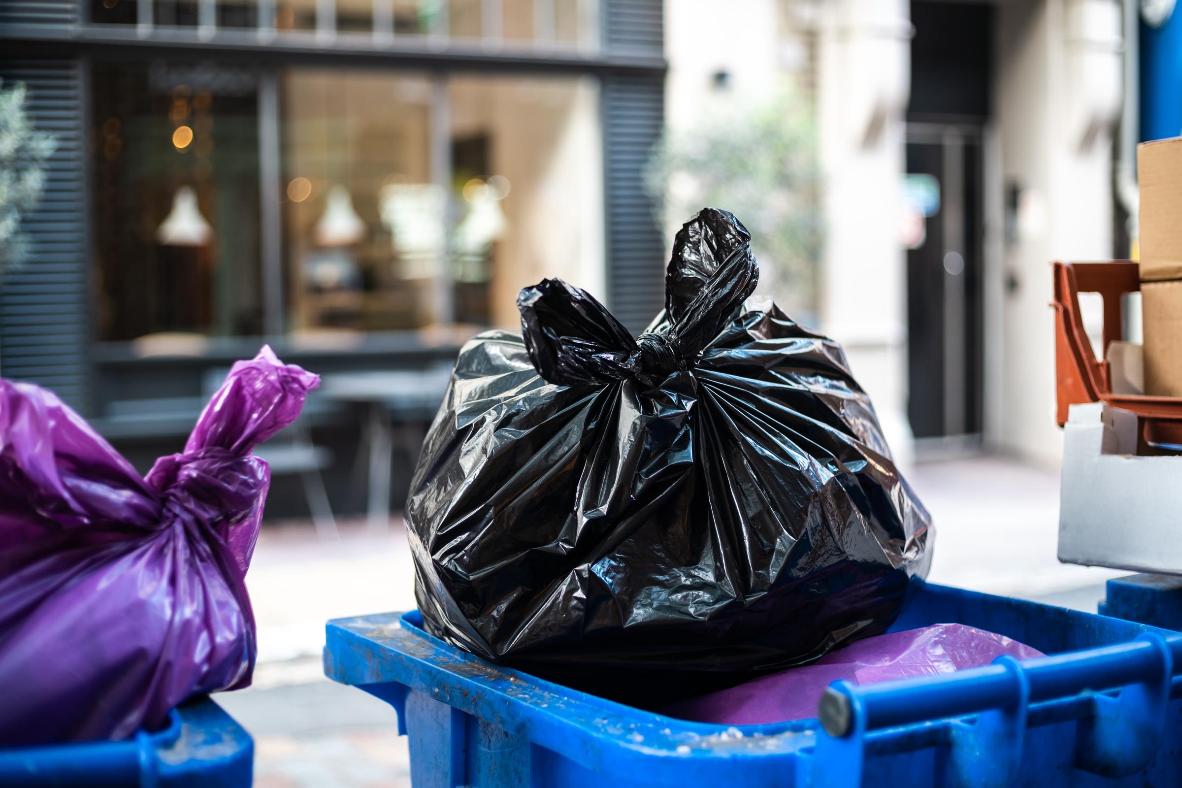Des sacs poubelles violets et noirs posés sur une poubelle | Source : Magnific
