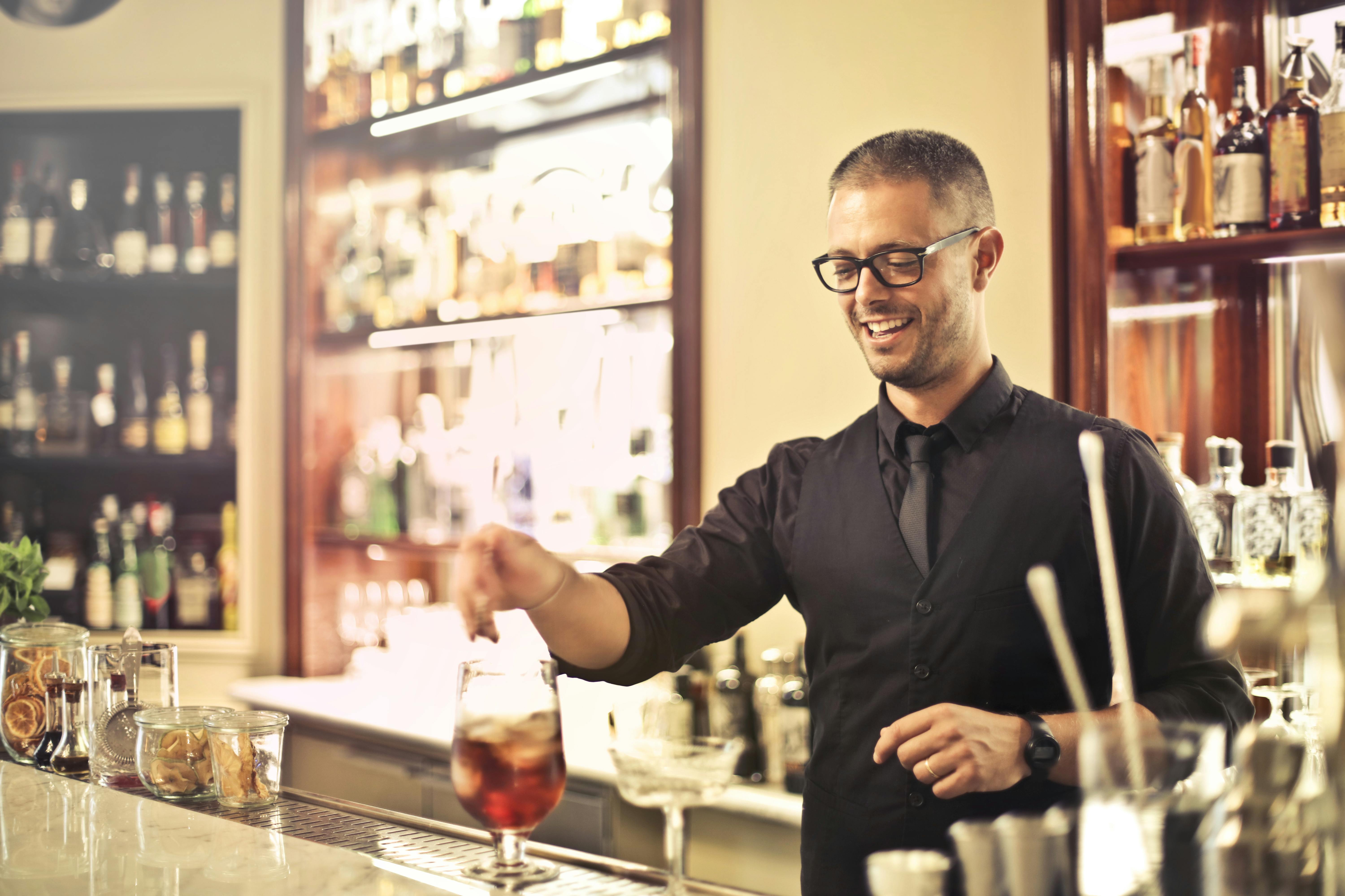Un serveur souriant préparant une boisson | Source : Pexels