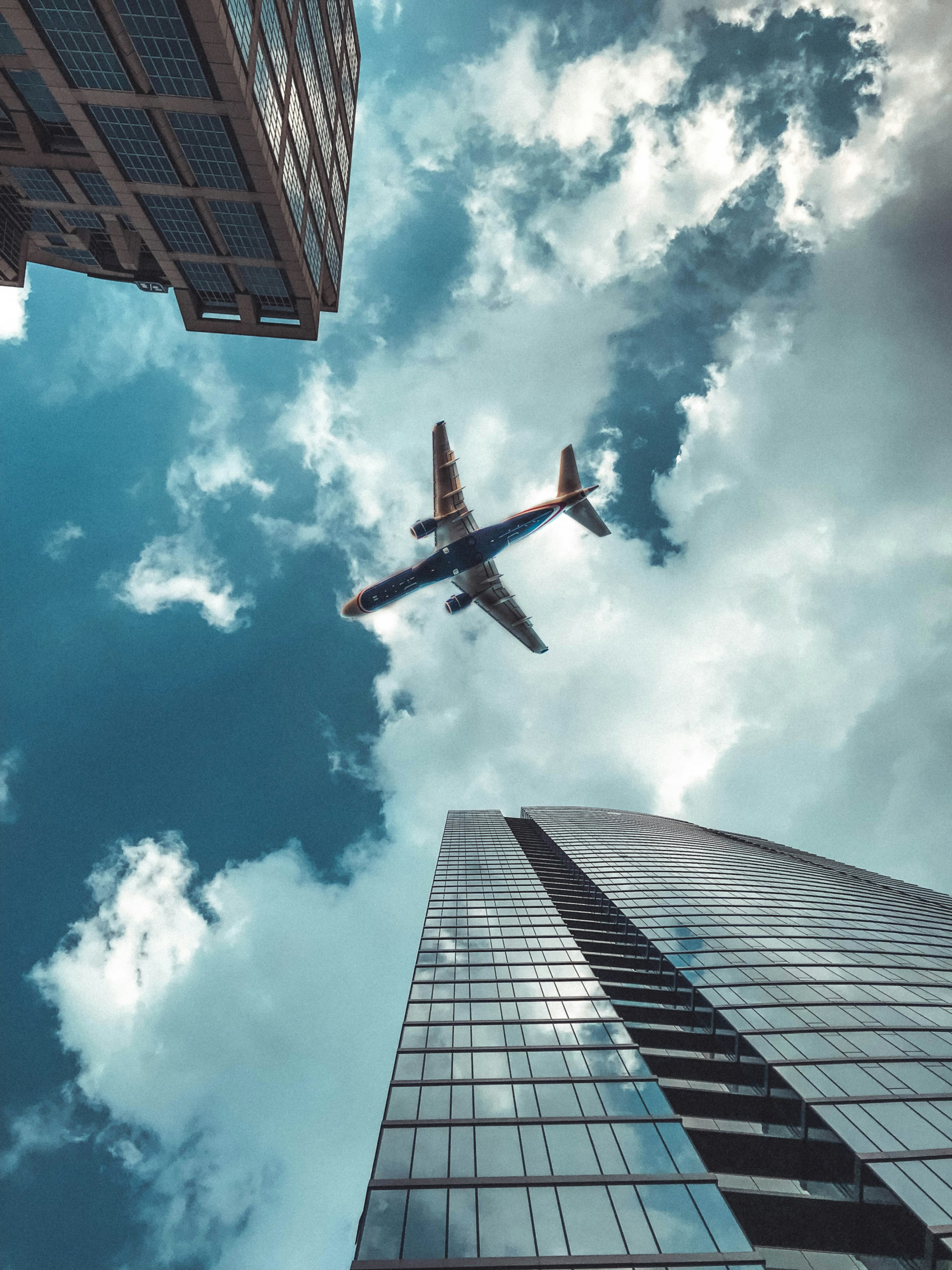 Prise de vue d'un avion passant au-dessus d'immeubles de grande hauteur | Source : Unsplash