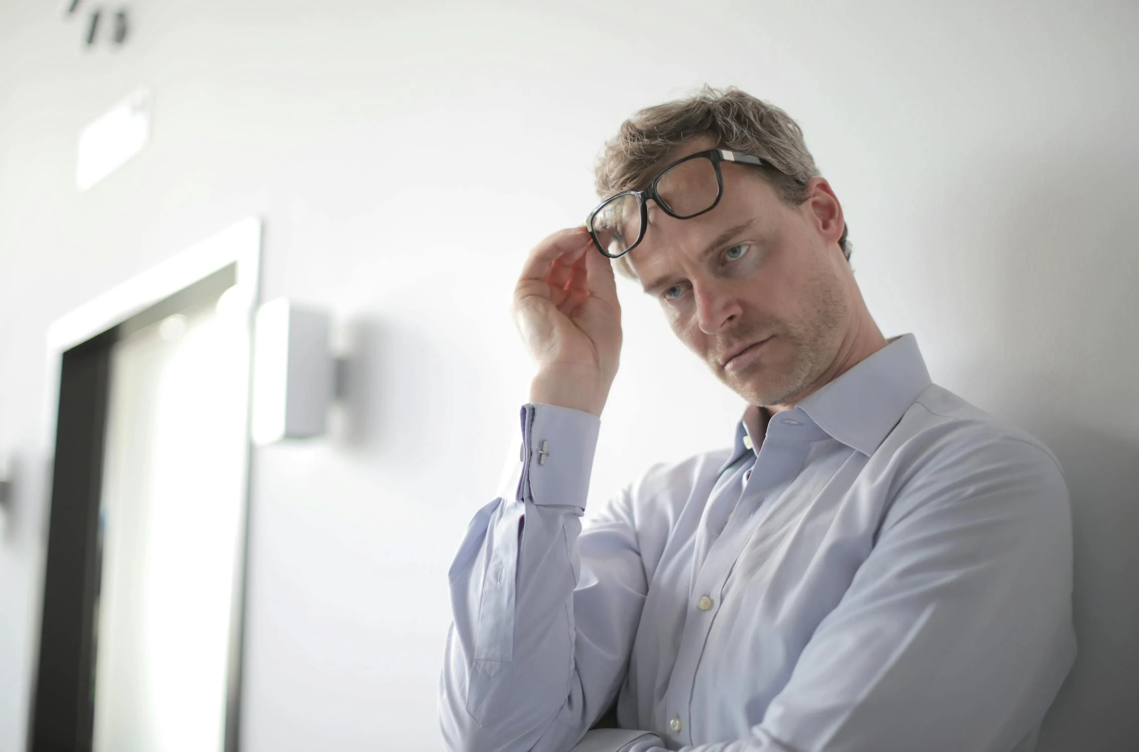 A serious man lifting his glasses ⏐ Source: Pexels