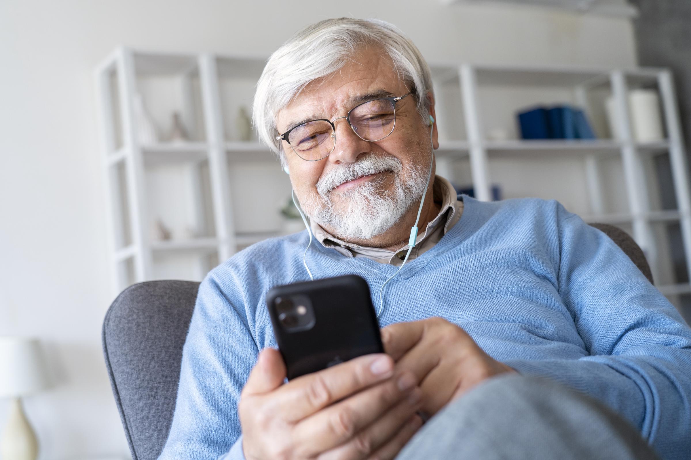 Un homme âgé regardant son téléphone et souriant | Source : Freepik