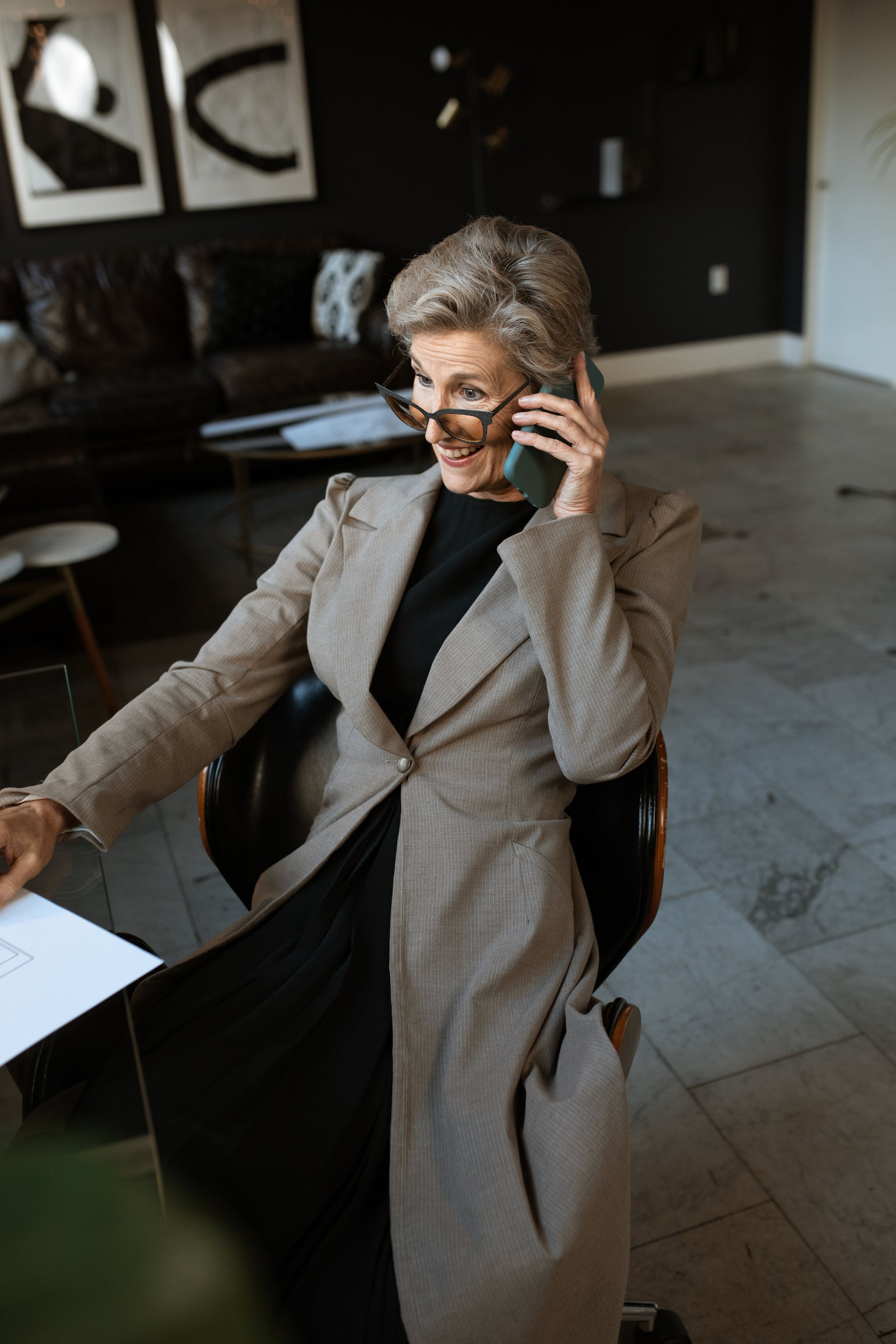 Une femme âgée en manteau gris assise tout en parlant au téléphone | Source : Pexels