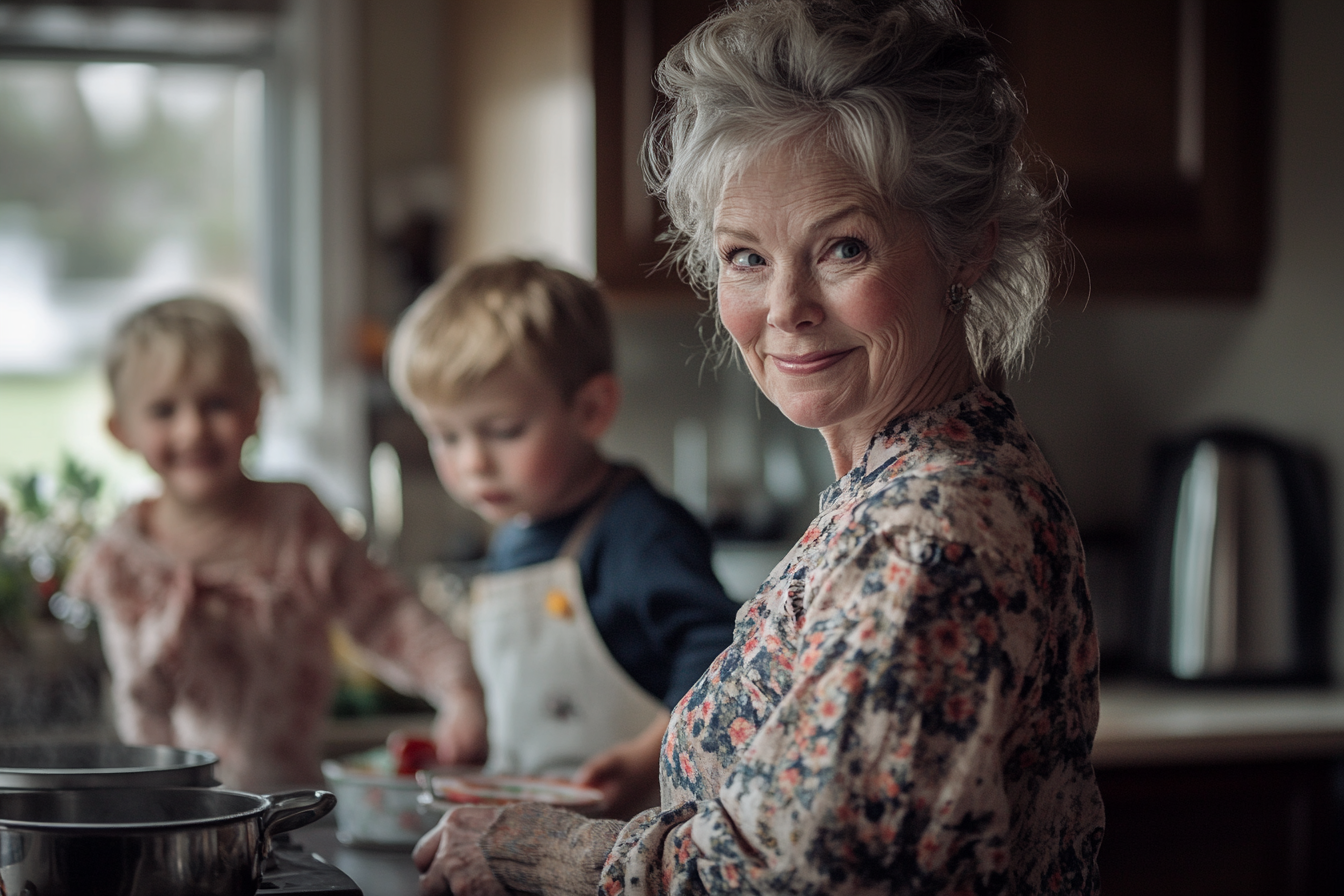 Femme d'une soixantaine d'années souriant et cuisinant dans une cuisine avec deux enfants en arrière-plan | Source : Midjourney