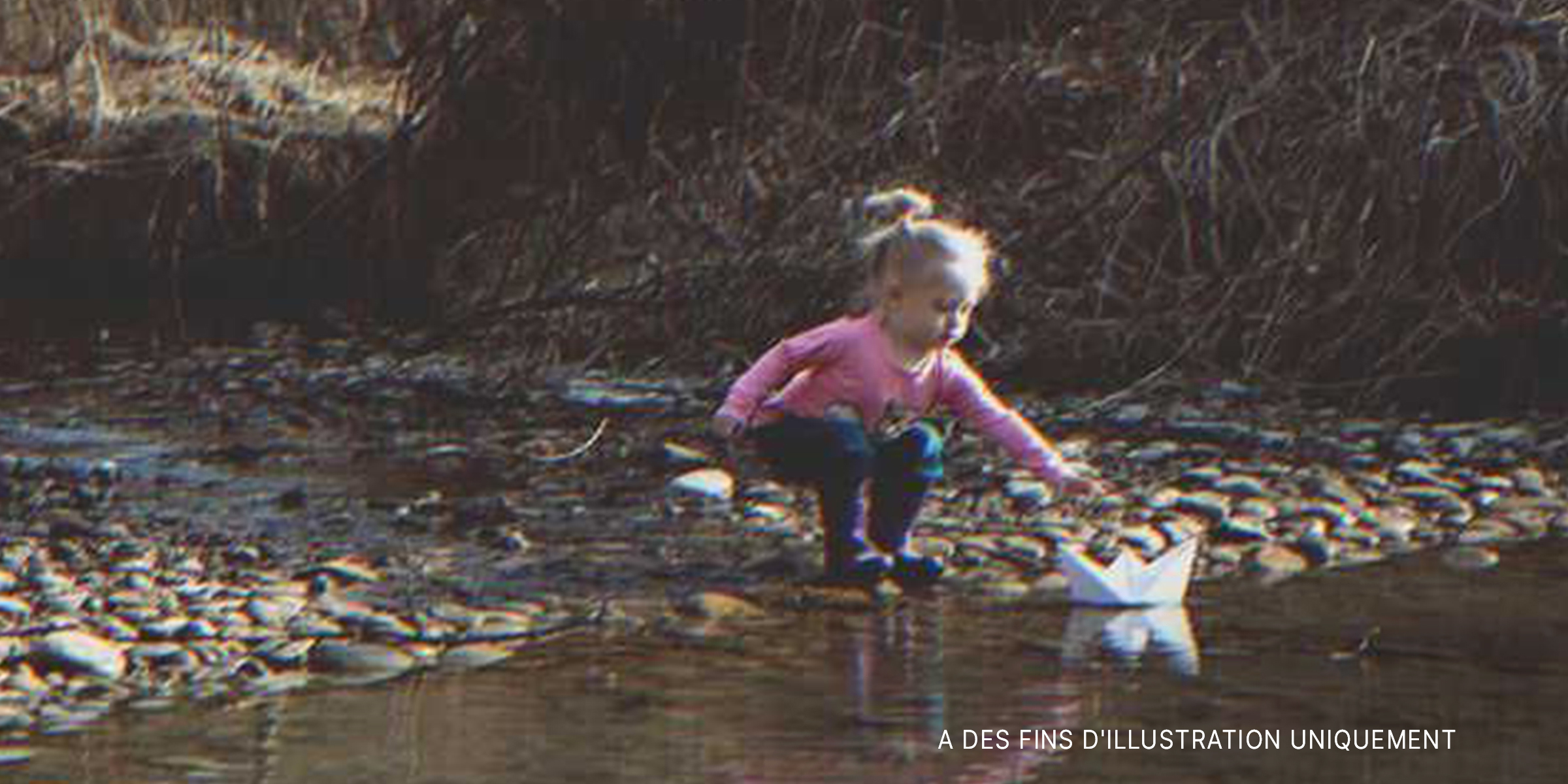 Une petite fille trouvant un bateau en papier sur la rivière | Source : Shutterstock