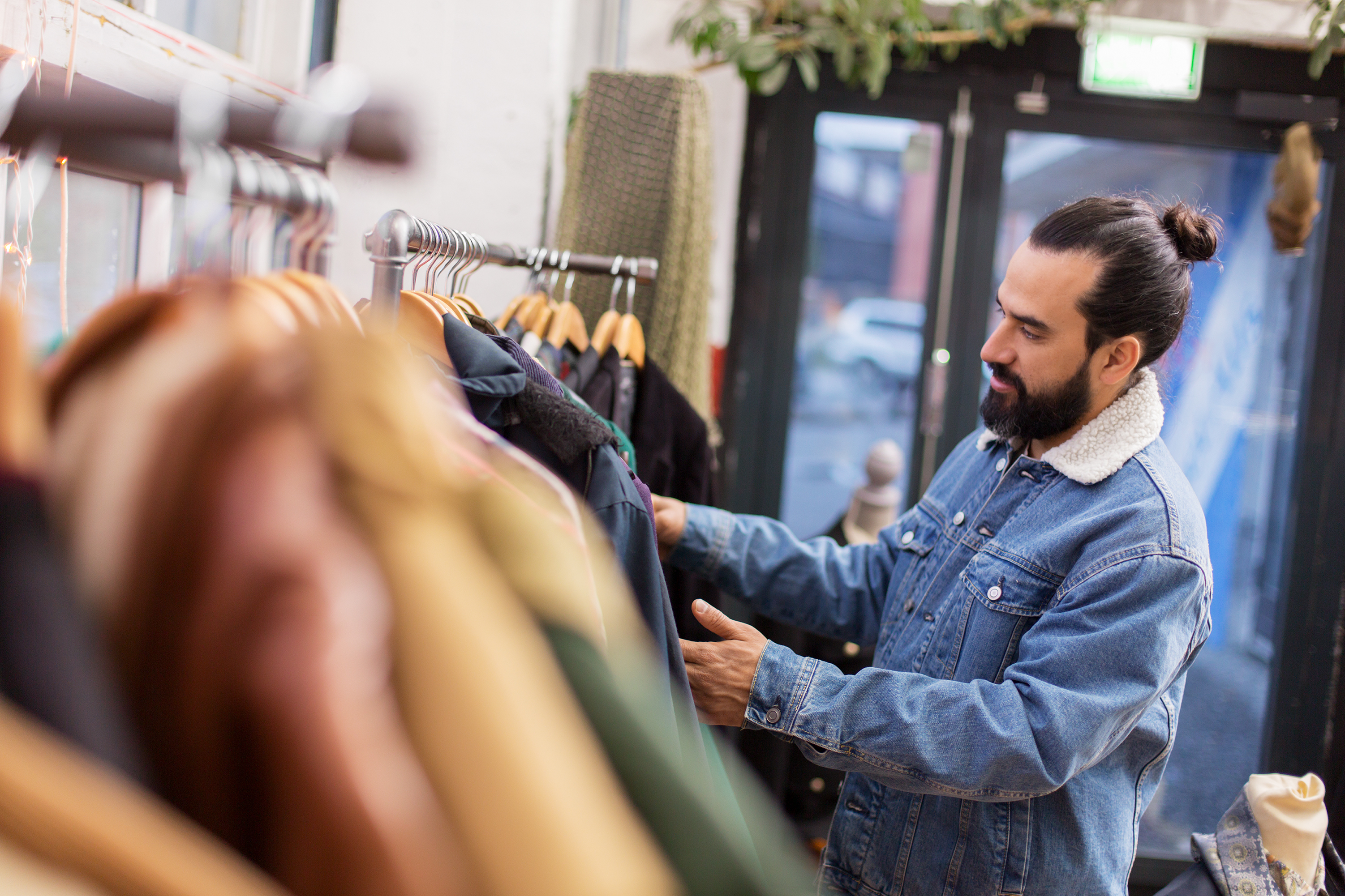 Hombre eligiendo ropa en una tienda de ropa vintage | Fuente: Shutterstock.com