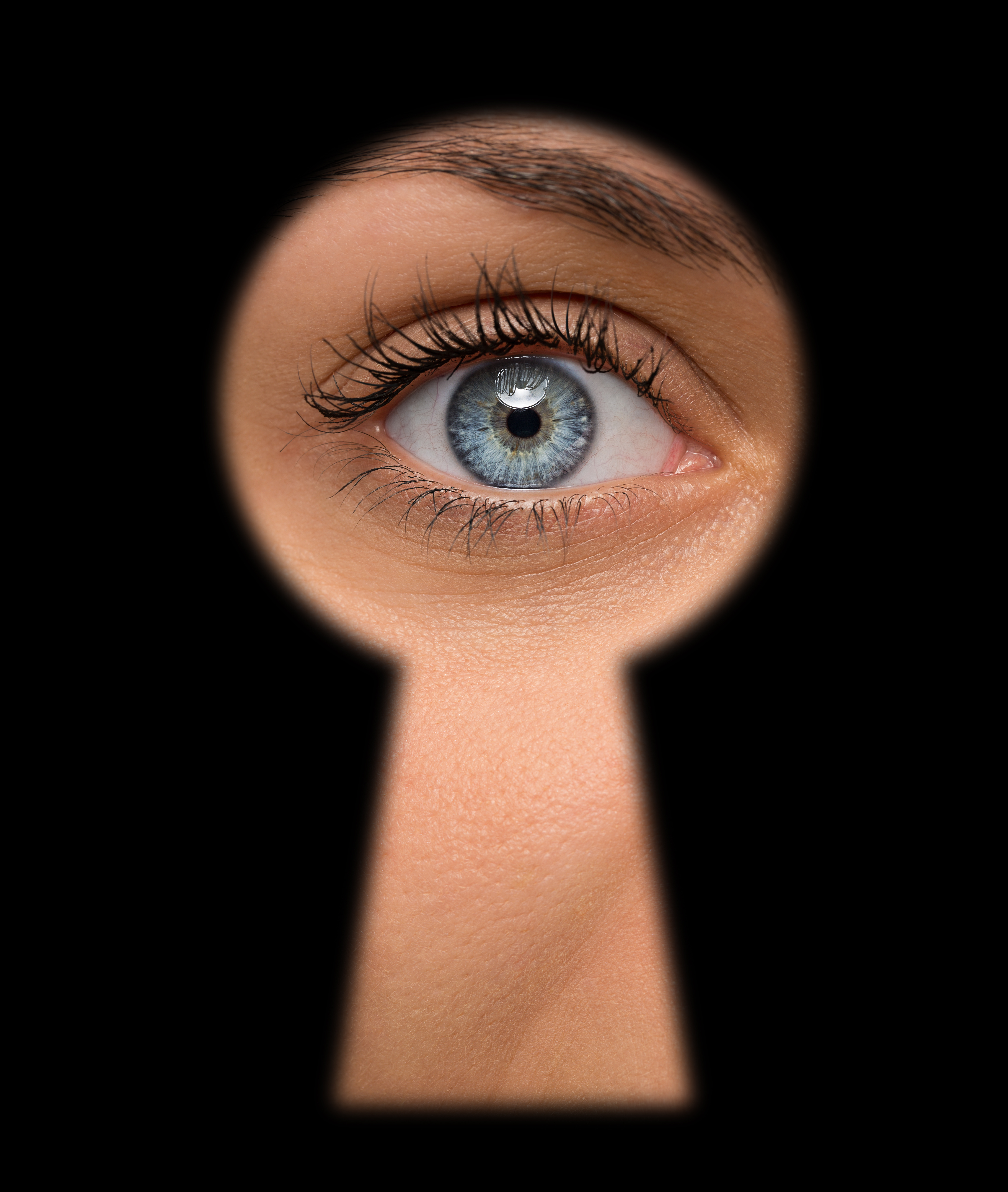 Une femme aux yeux bleus jette un coup d'œil à travers un trou de serrure | Source : Shutterstock