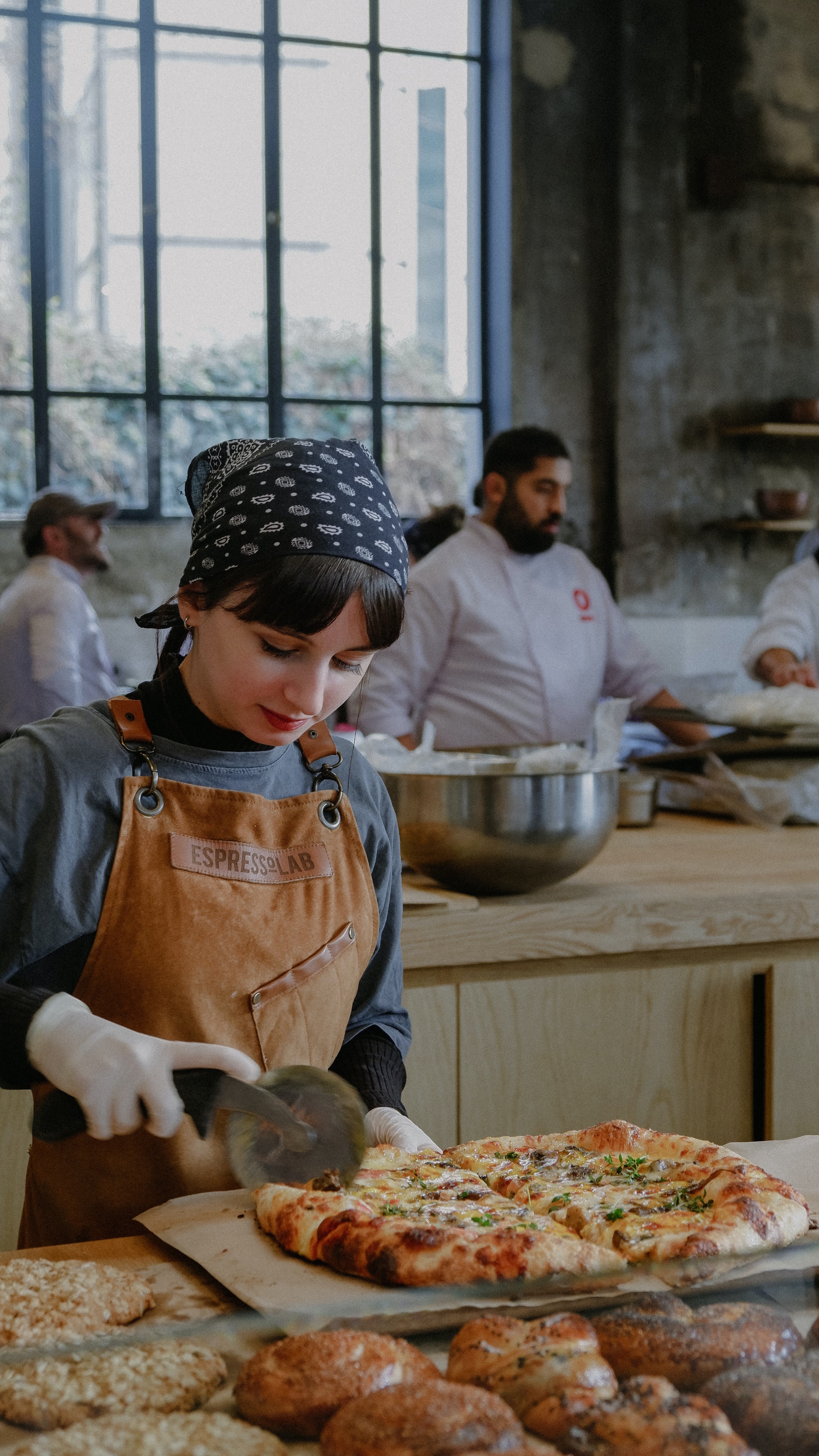 Una mujer cortando pizza en la cocina de un restaurante | Fuente: Pexels