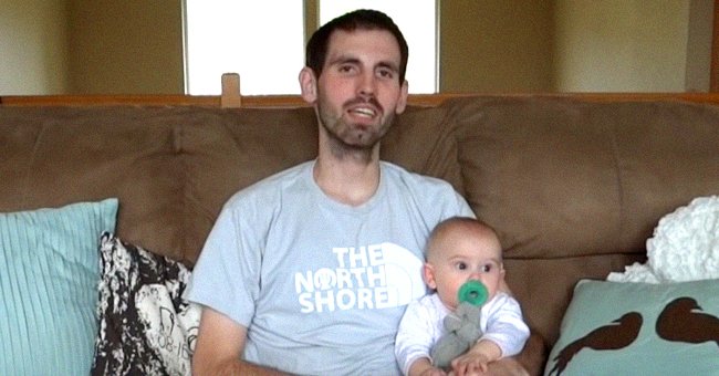 Nick Magnotti assis sur un canapé en tenant dans ses bras sa petite fille de 7 mois, Austin. │Source : youtube.com/Alyssa Galios