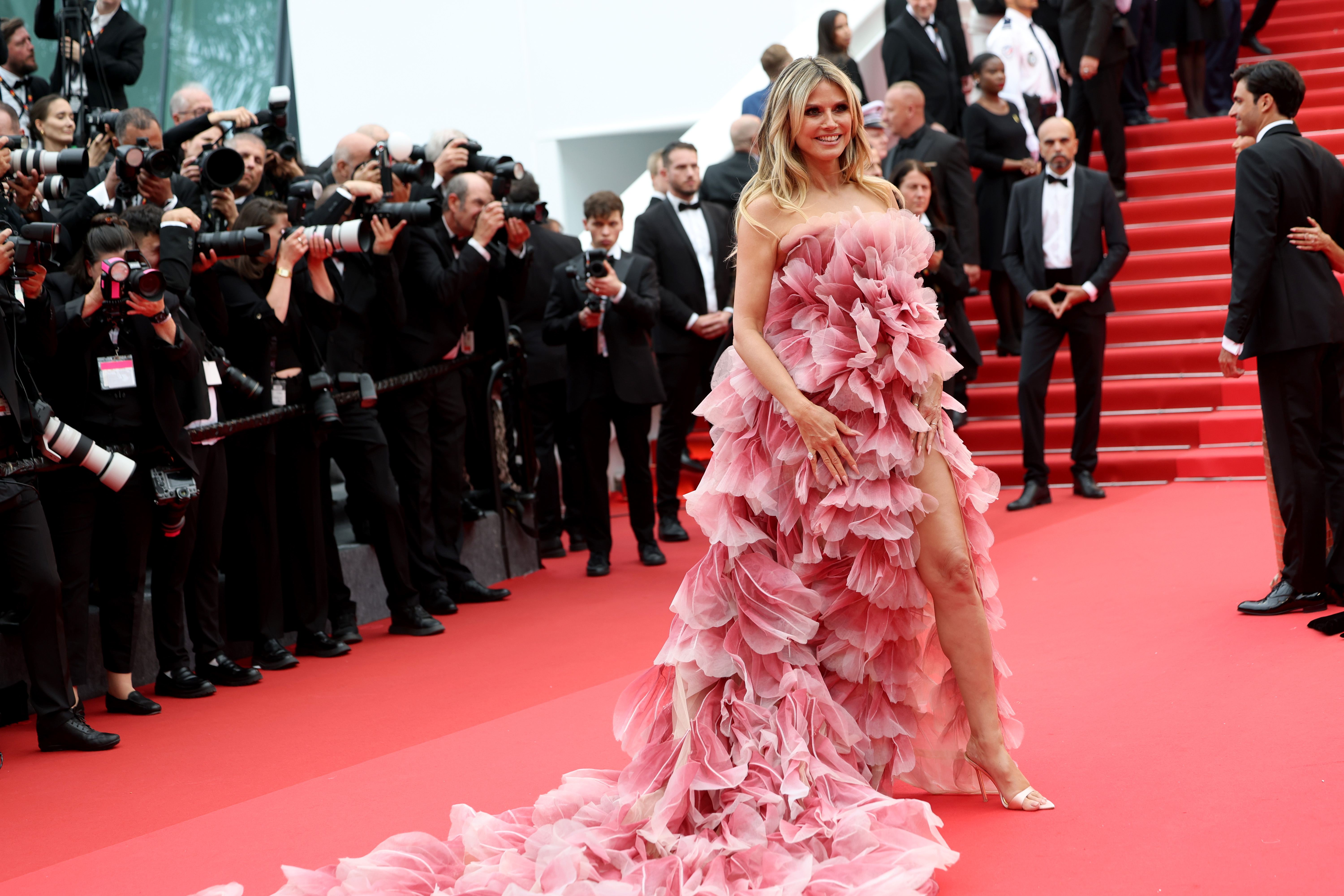 Heidi Klum sourit, savourant manifestement le moment et l'attention qui l'accompagne. Une jambe passe à travers la fente de sa robe à hauteur des cuisses, révélant un talon aiguille argenté scintillant qui ajoute à l'effet dramatique de son look.