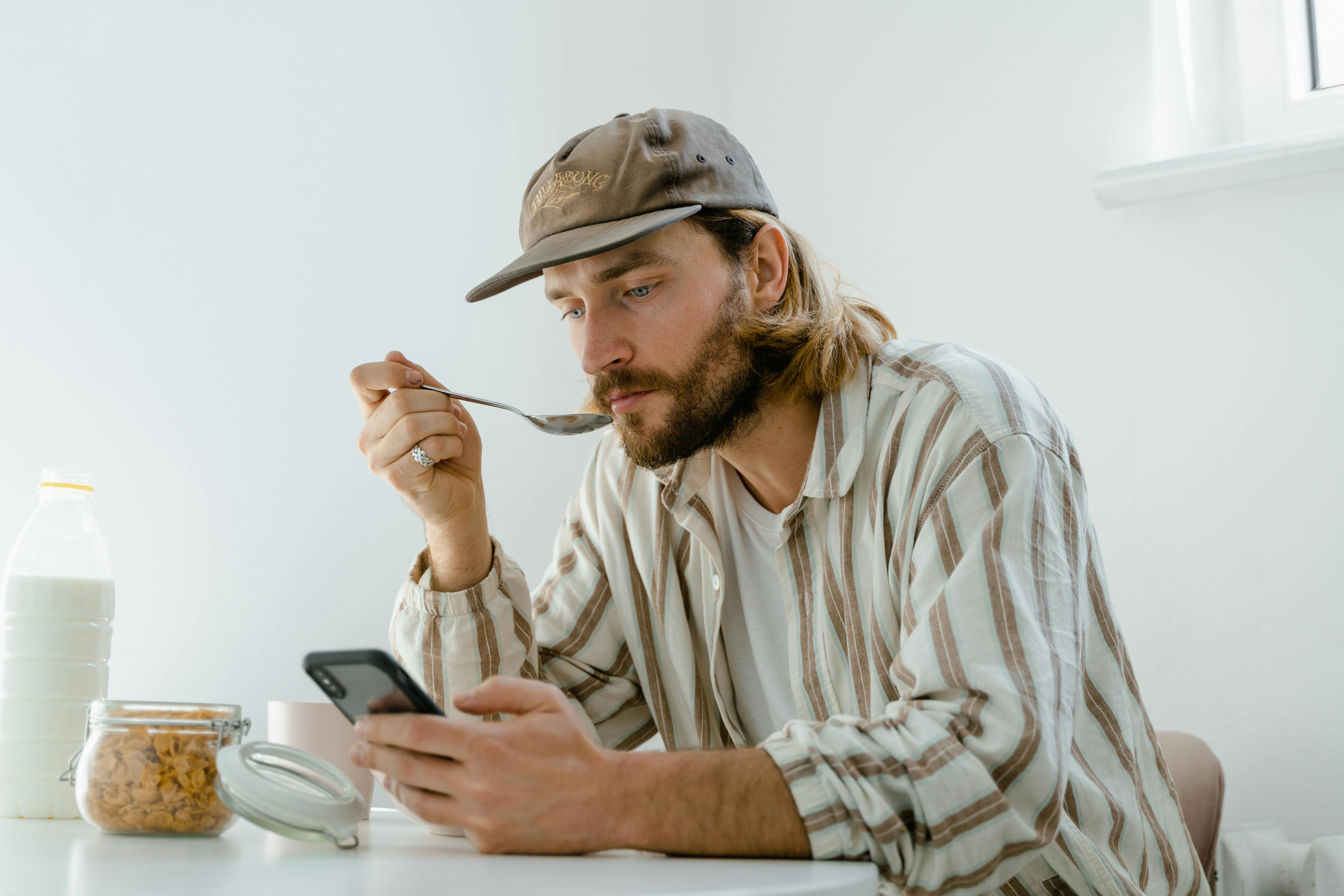 Un homme envoie des textos tout en prenant son petit déjeuner | Source : Pexels