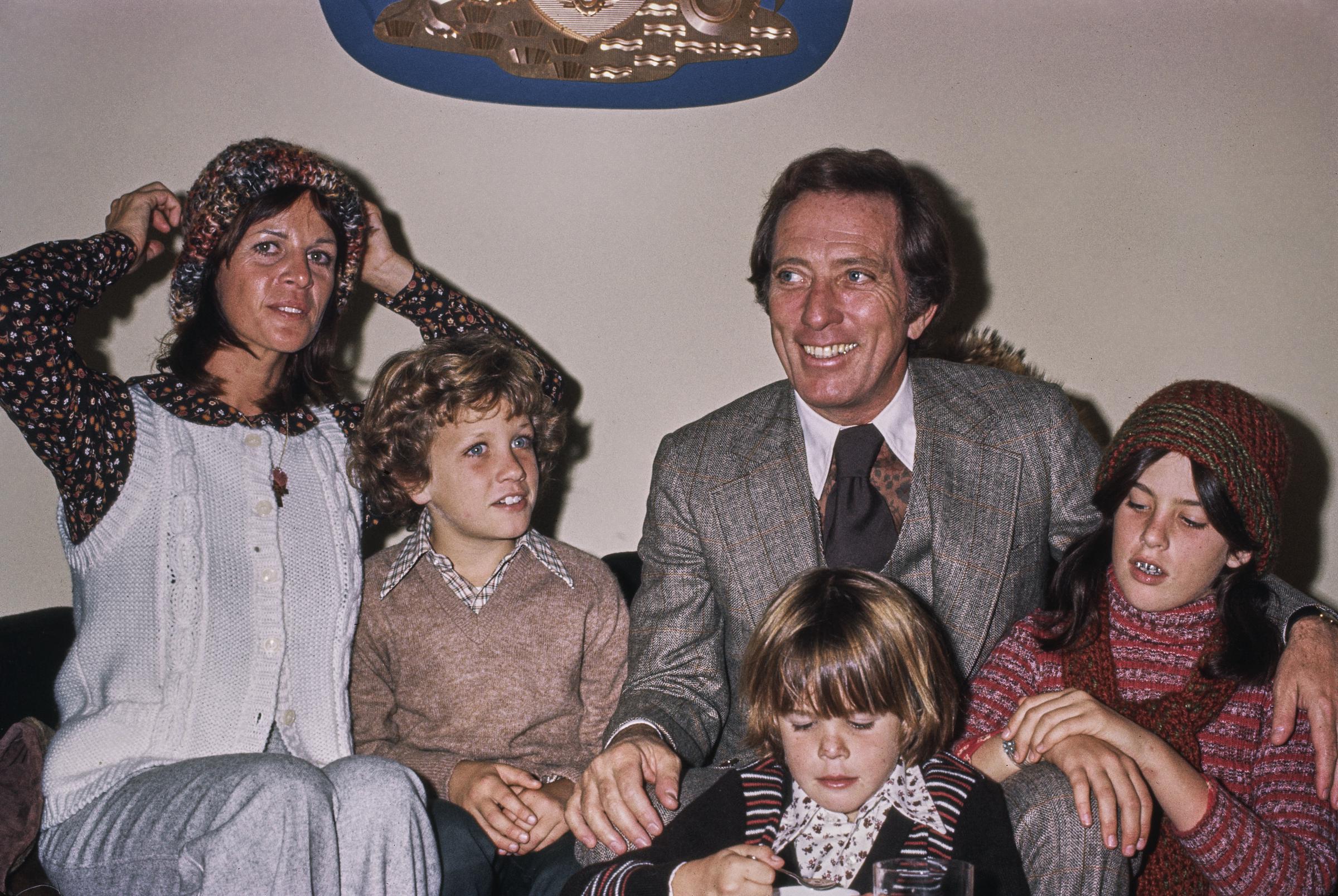 La chanteuse, actrice et danseuse franco-américaine Claudine Longet, vêtue d'un gilet en tricot blanc sur une blouse à motifs et d'un bonnet en tricot, et son mari, le chanteur américain Andy Williams, qui porte un costume gris et un gilet sur une chemise marron à motifs avec un col blanc et une cravate noire, en compagnie de leurs enfants, Christian, Robert et Noelle, aux États-Unis, vers 1970 I Source : Getty Images