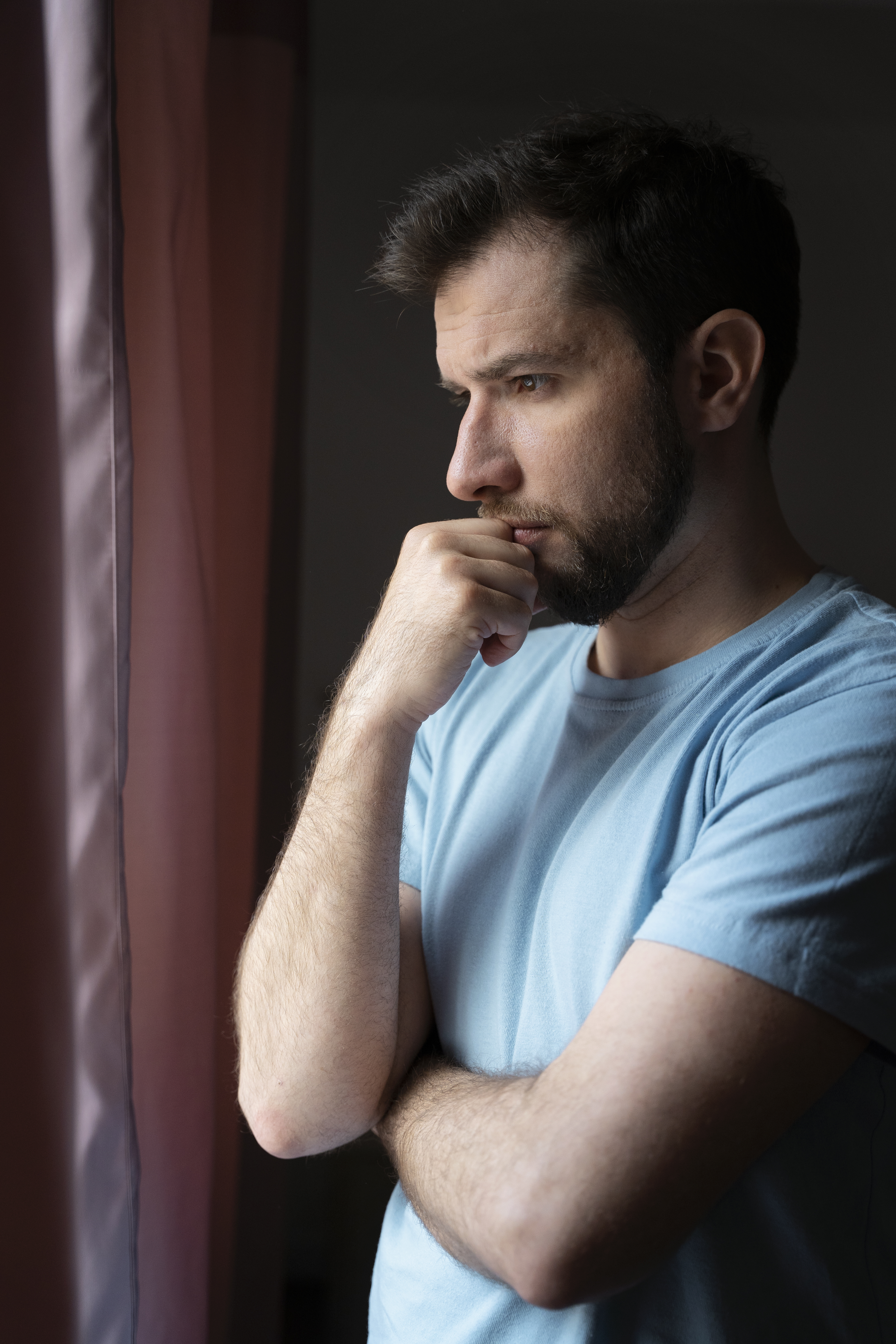 Homme réfléchissant face à une fenêtre | Source : Freepik.com