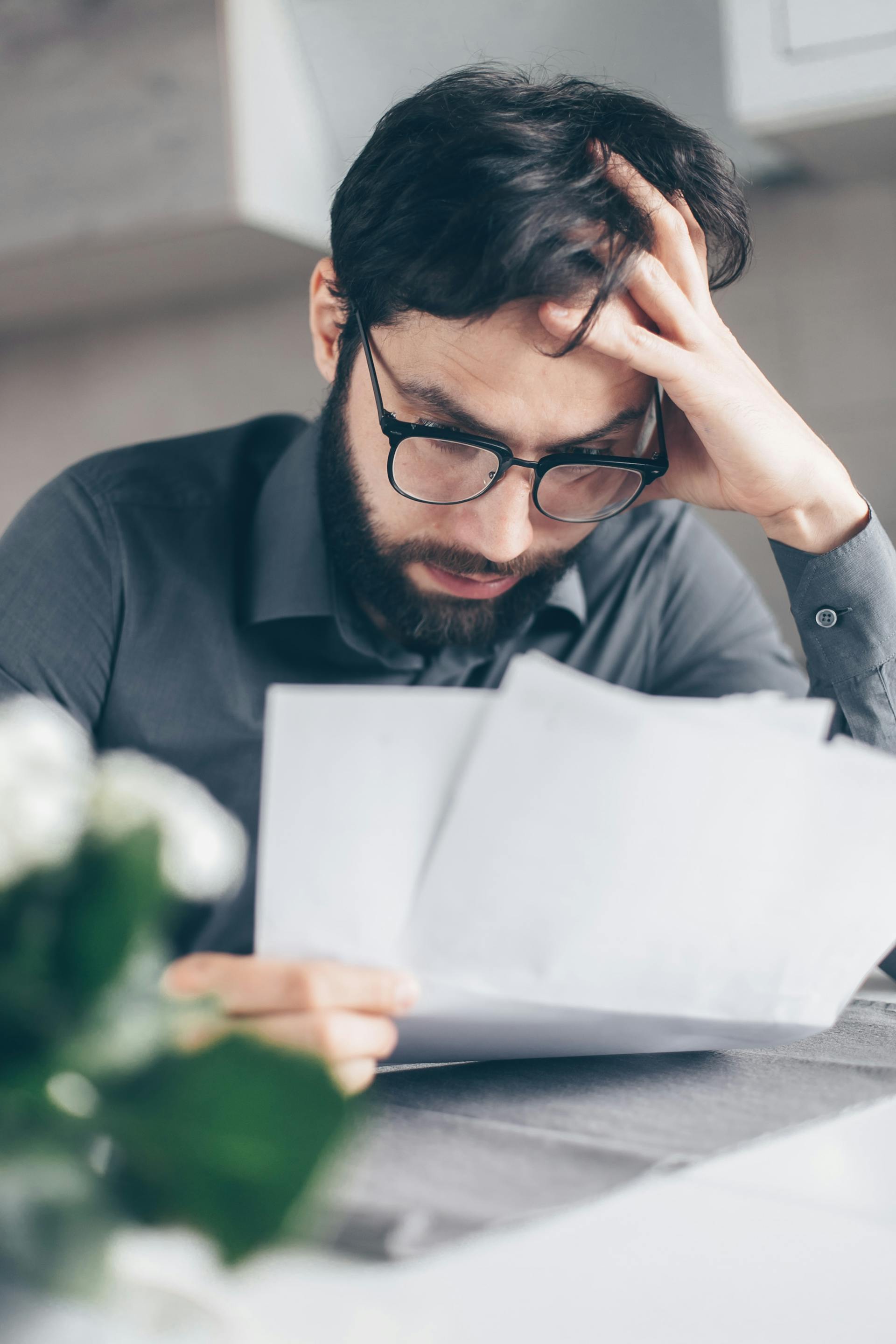 Een man kijkt geschokt terwijl hij de documenten leest die hij in zijn hand houdt | Bron: Pexels