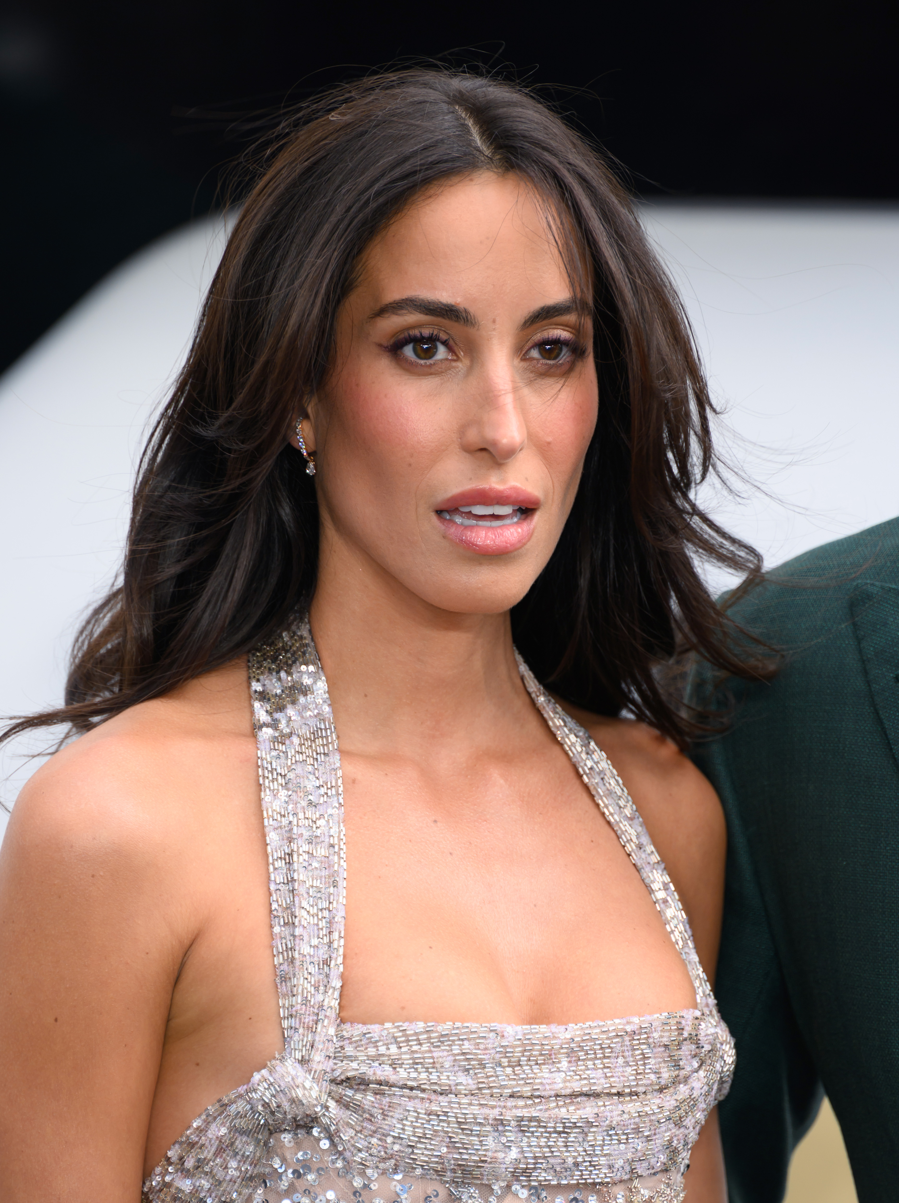 Ines de Ramon pose dans une robe argentée scintillante lors de la première londonienne du film « F1 : The Movie » ; de légères boucles encadrent son visage tandis qu'elle regarde les photographes sur le tapis rouge.