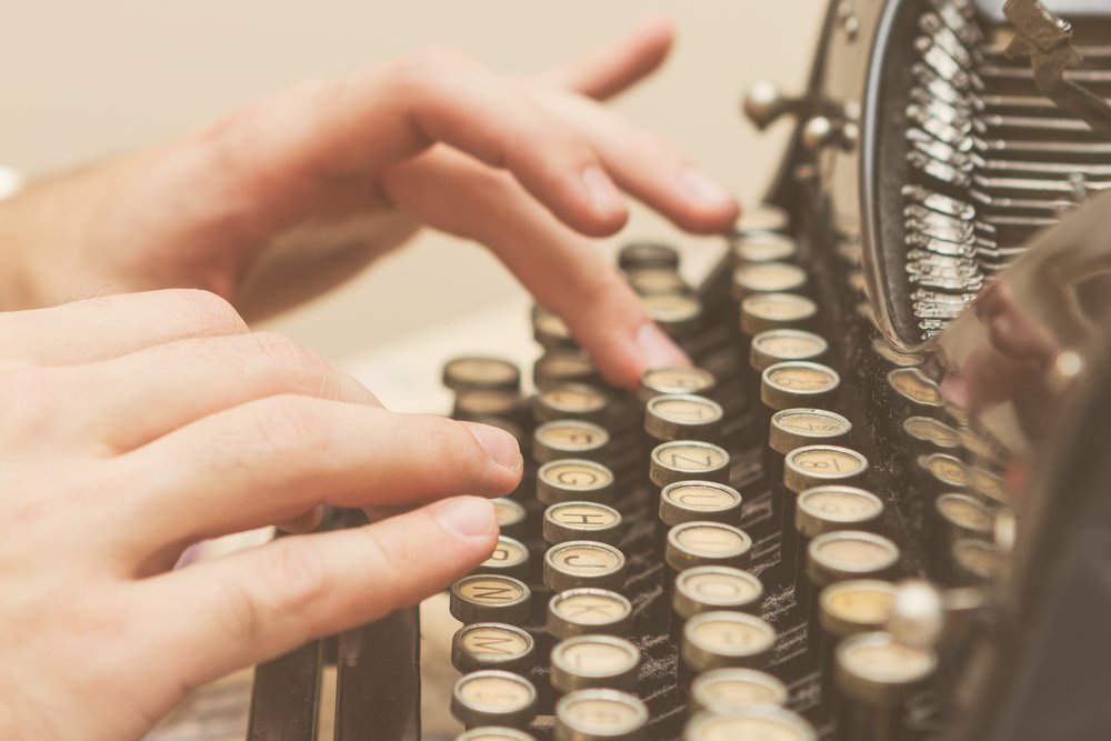 Mains écrivant sur une vieille machine à écrire | Shutterstock