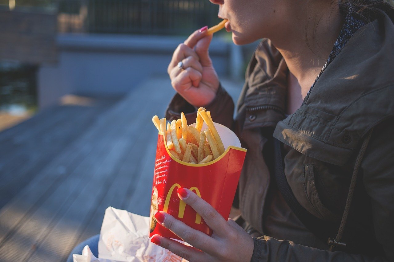 Une adolescente mangeant des frites | Photo: Pixabay