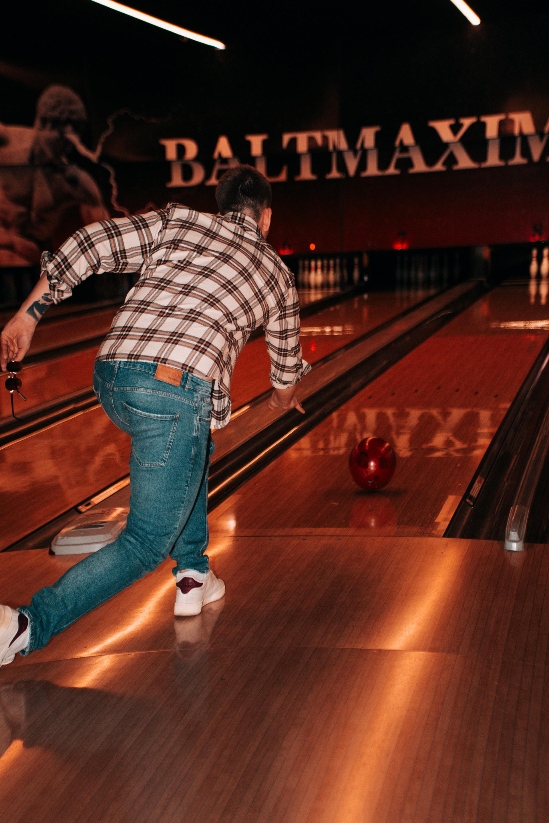 Vue arrière d'un homme lançant une boule dans un bowling | Source : Pexels