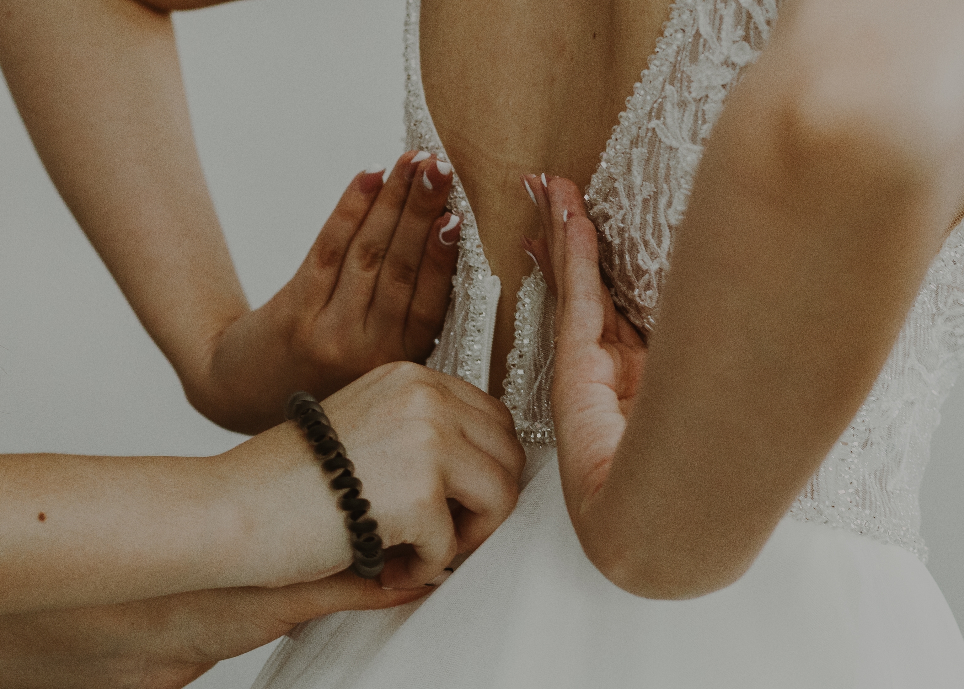 Une personne aidant une mariée à fermer la fermeture éclair de sa robe | Source : Shutterstock