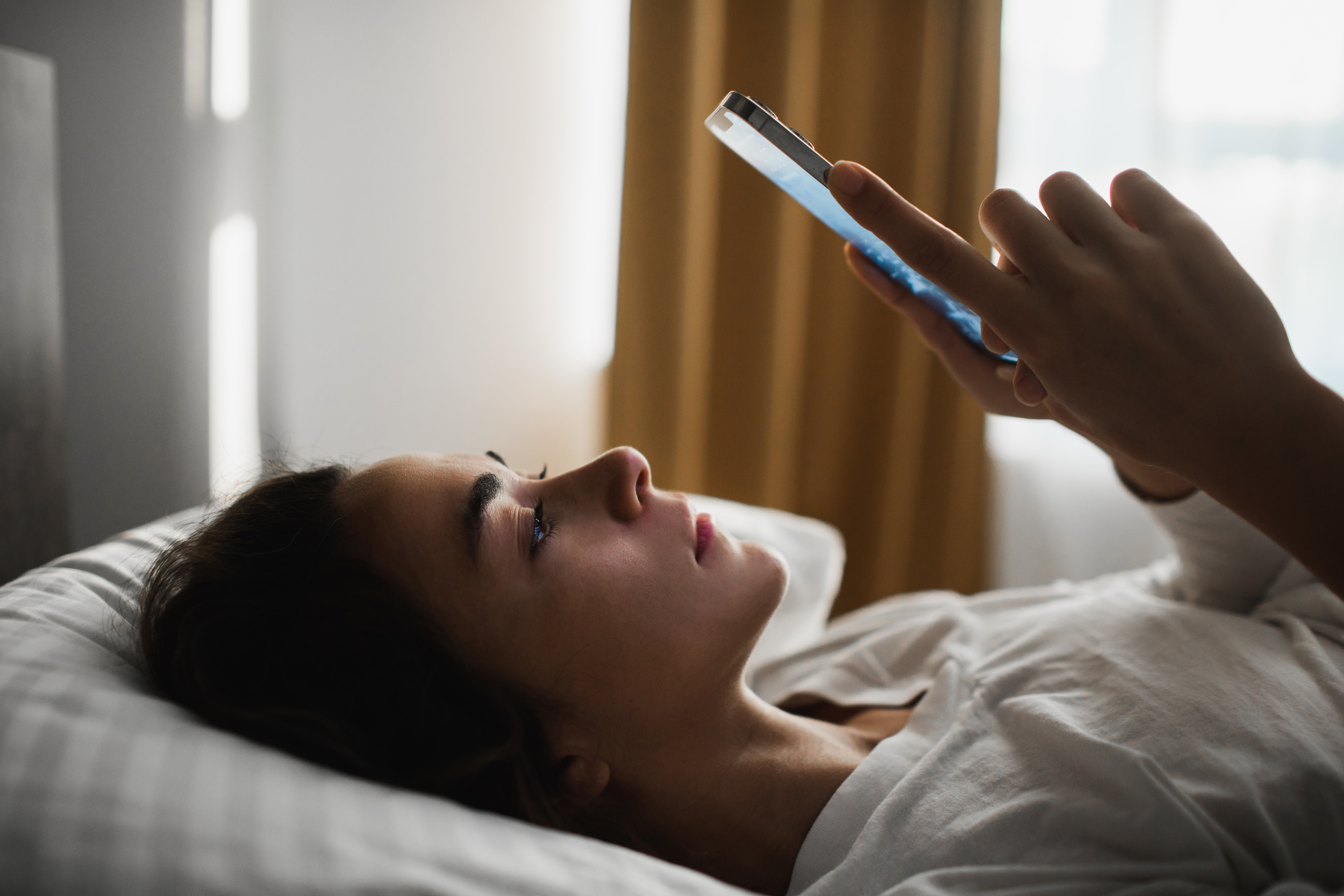 Une femme au lit regardant son téléphone | Source : Getty Images