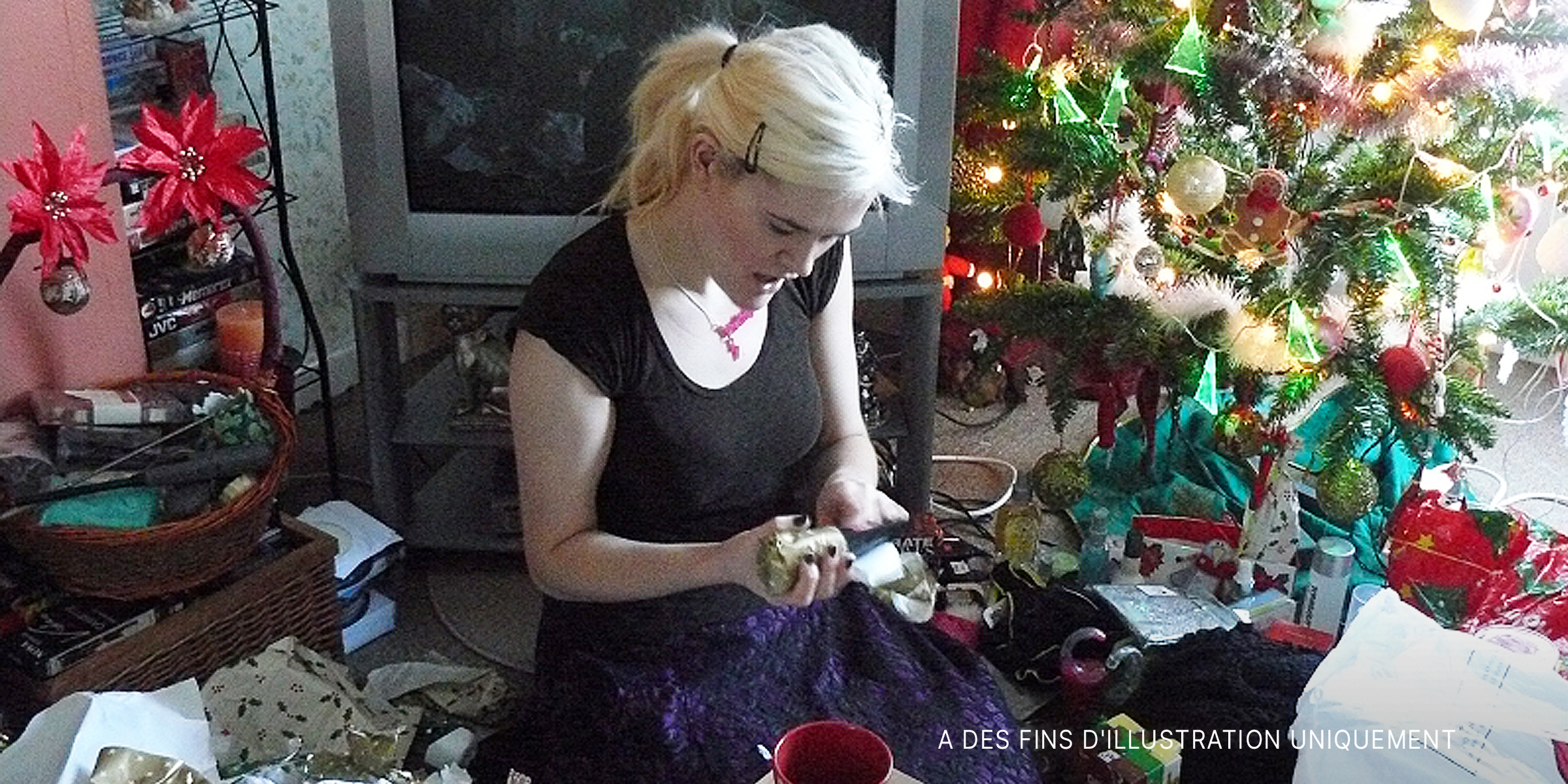 Une jeune femme déballe un cadeau de Noël | Source : Flickr.com/flem007_uk/CC BY-ND 2.0