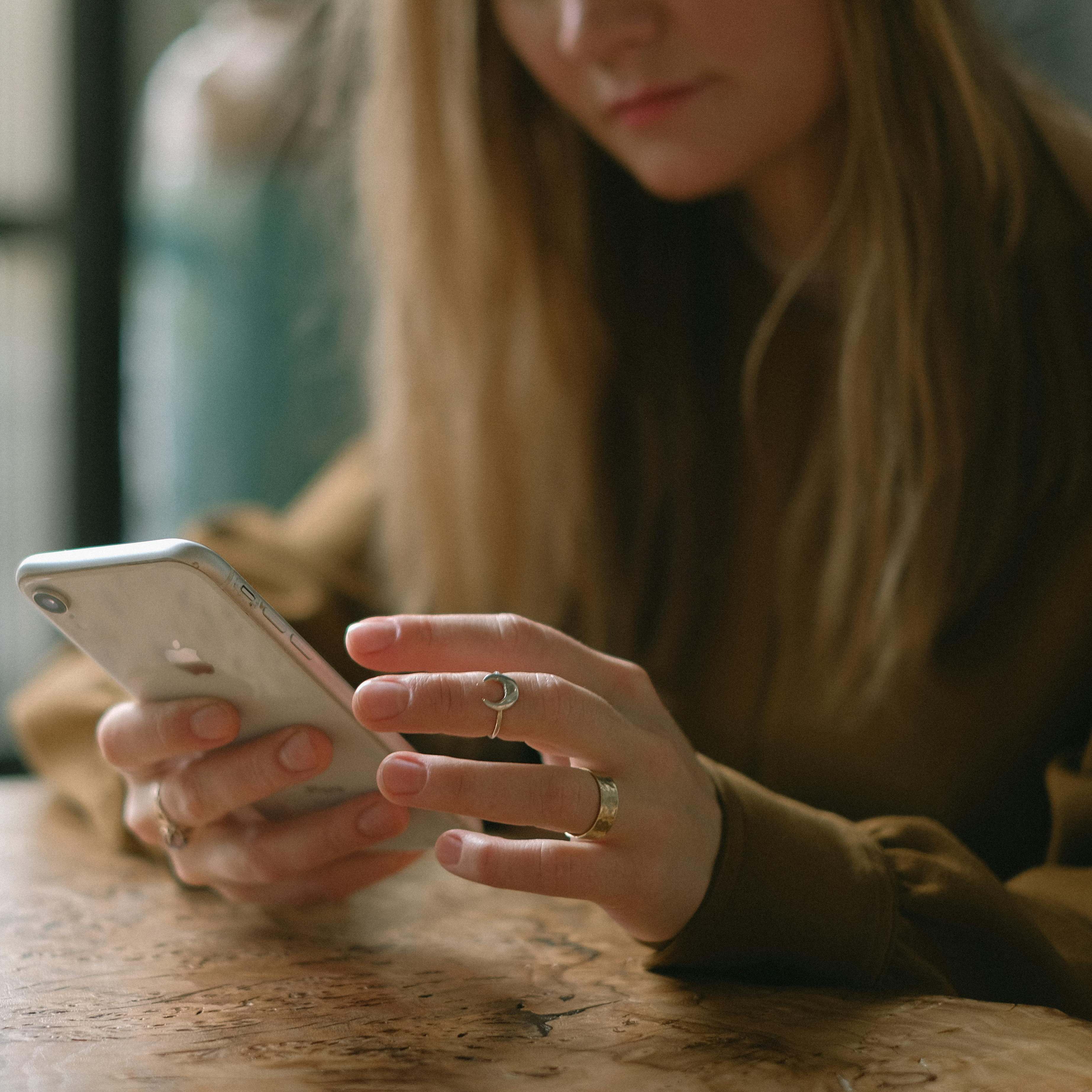 Une femme assise à la table d'un restaurant, regardant son téléphone | Source : Pexels