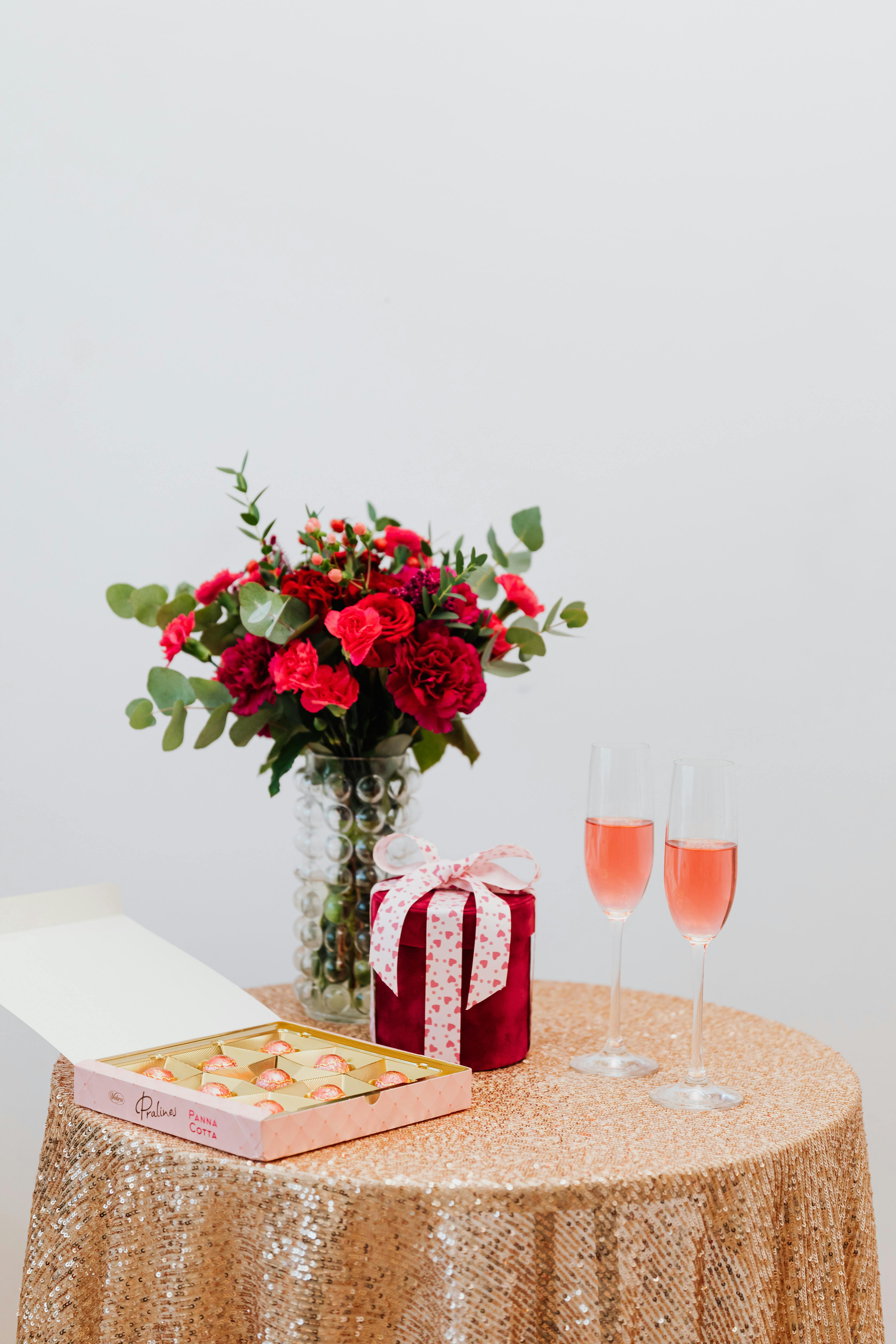 Des fleurs, des chocolats, un cadeau et des coupes de champagne sur une table | Source : Pexels