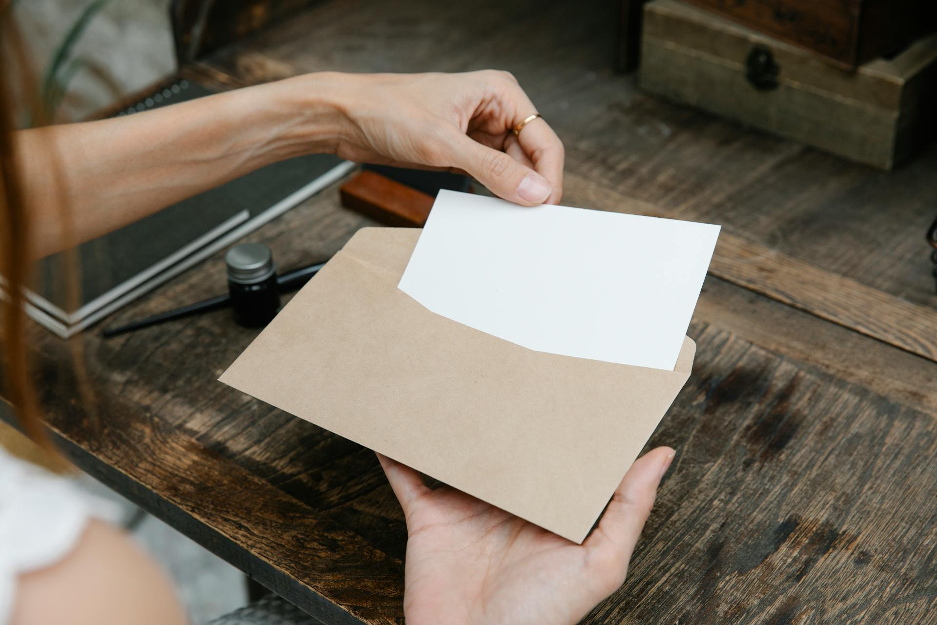 Une femme plaçant une lettre dans une enveloppe | Source : Pexels