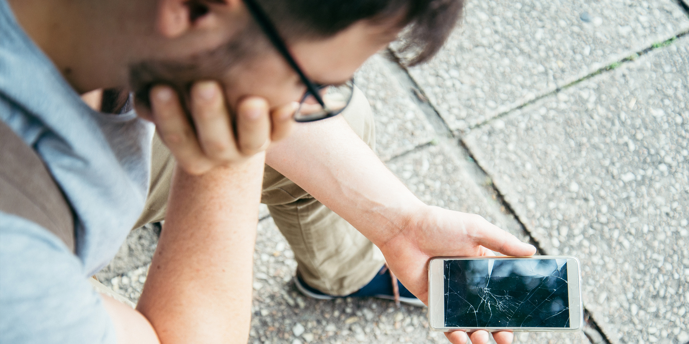 Un homme qui regarde un téléphone cassé | Source : Shutterstock