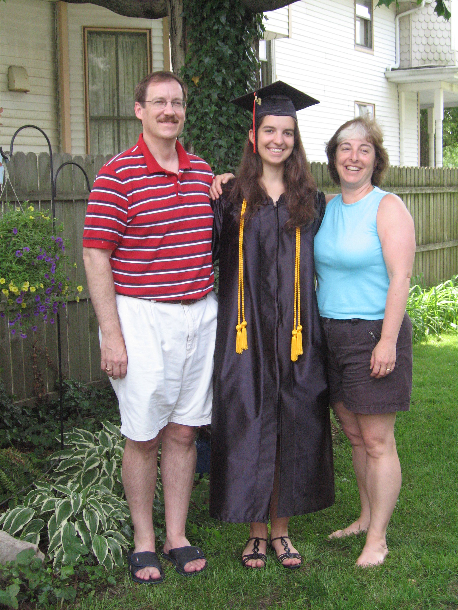 Une femme portant une robe et un chapeau de fin d'études à côté de ses parents | Source : flickr.com