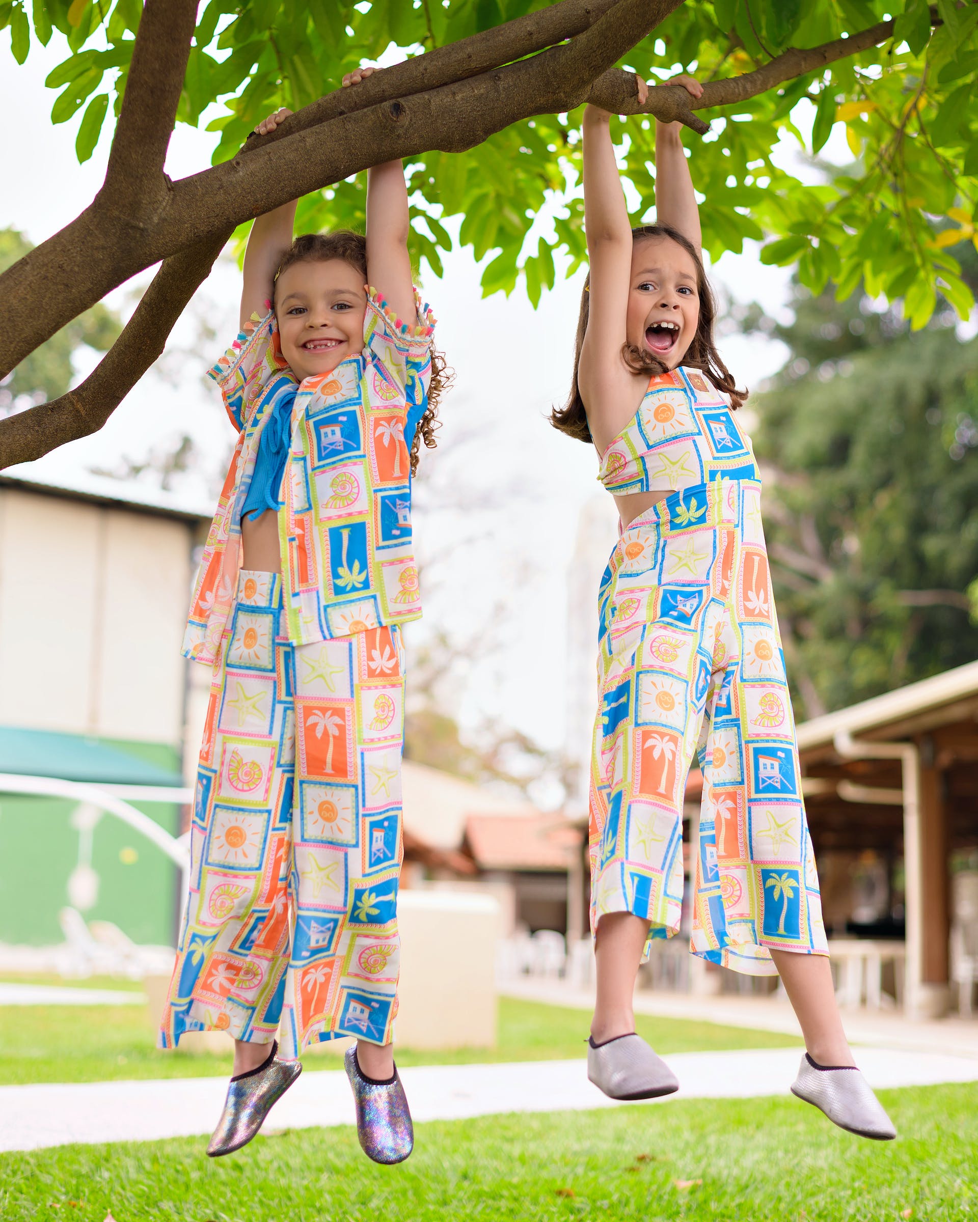 Deux jeunes filles souriantes portant la même robe sont suspendues à une branche d'arbre | Source : Pexels
