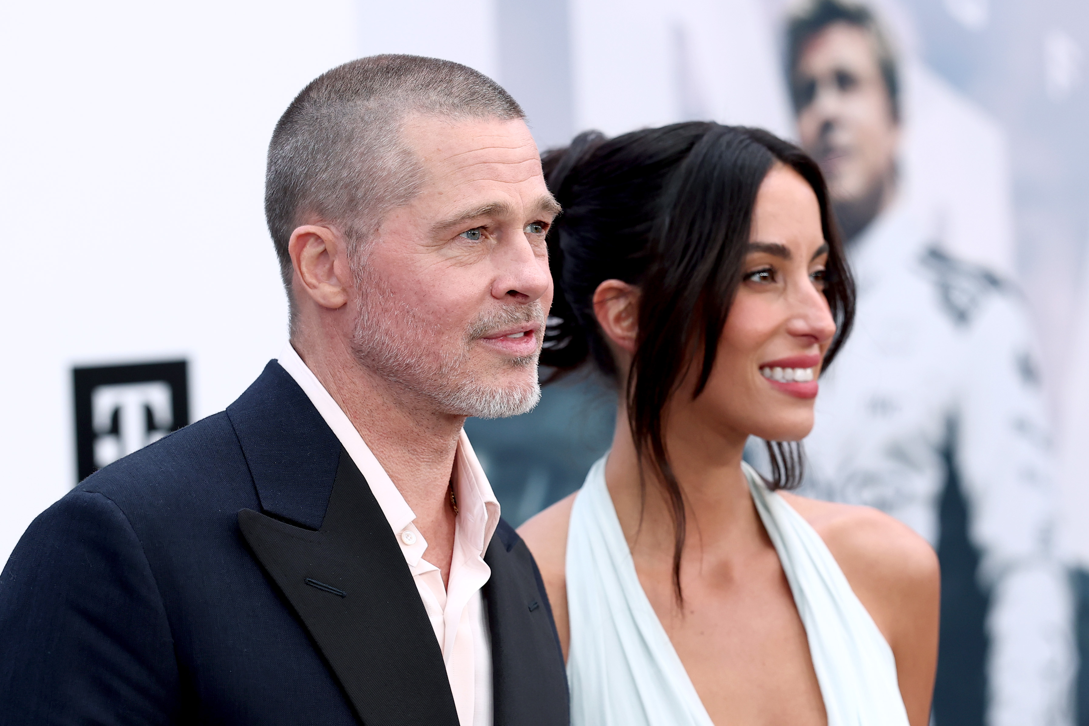 Brad Pitt et Ines de Ramon se tiennent côte à côte lors de la première mondiale du film « F1 » à New York ; Pitt porte un costume sombre et Inès de Ramon, souriante à ses côtés, une robe dos nu.