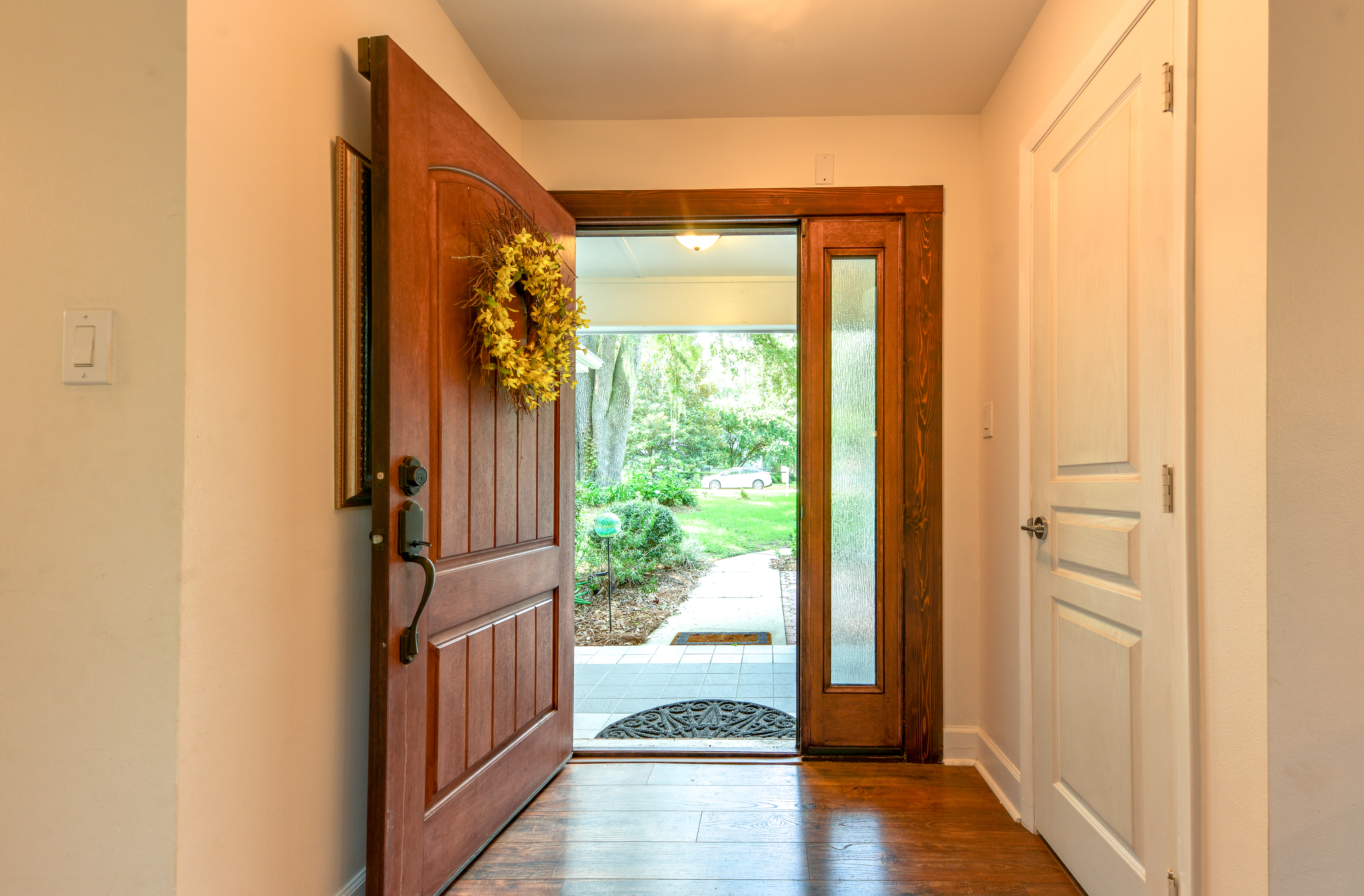 Une porte d'entrée ouverte avec une couronne de fleurs au-dessus | Source : Shutterstock