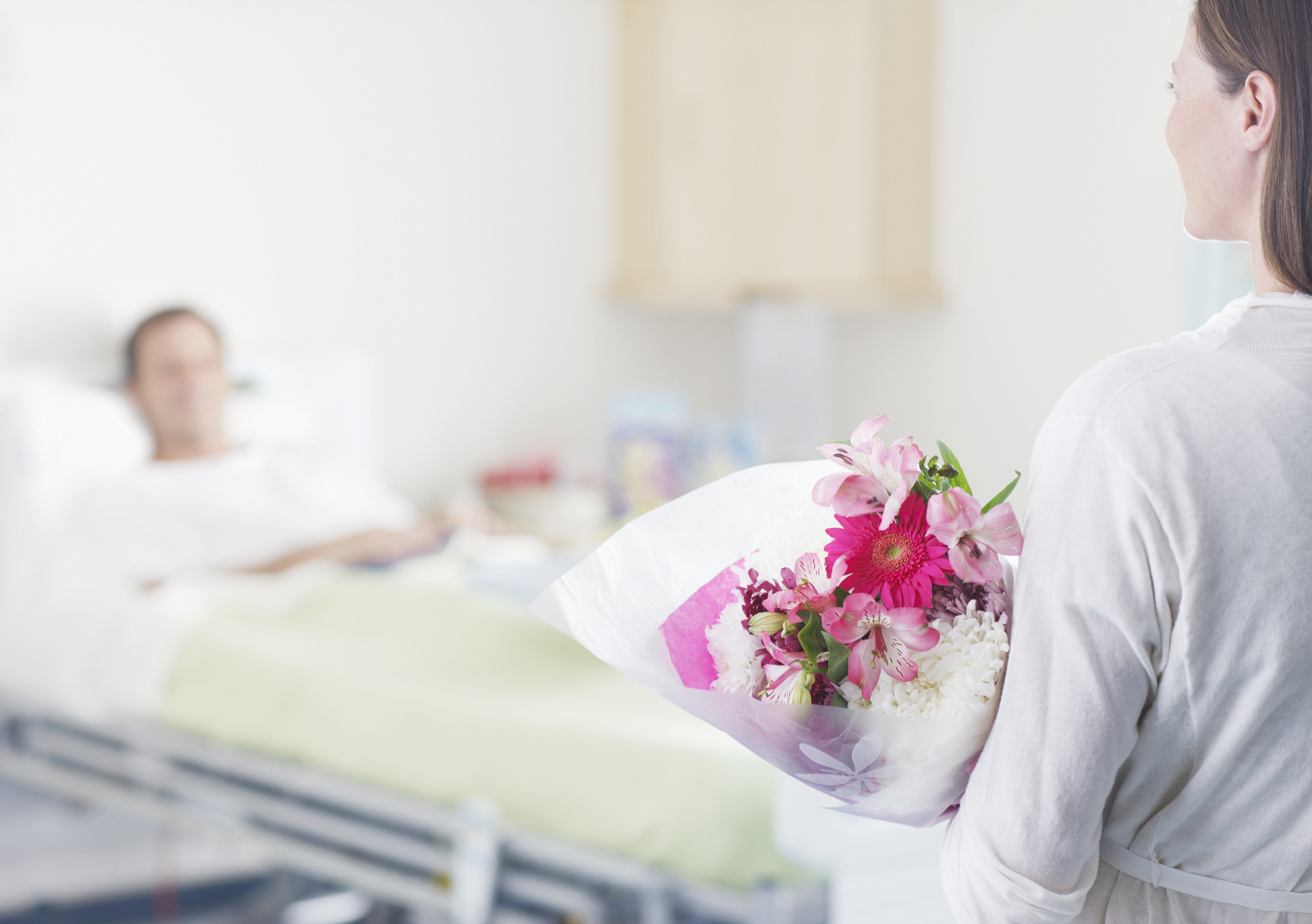 Une femme apportant des fleurs à un homme dans un hôpital | Source : Getty Images