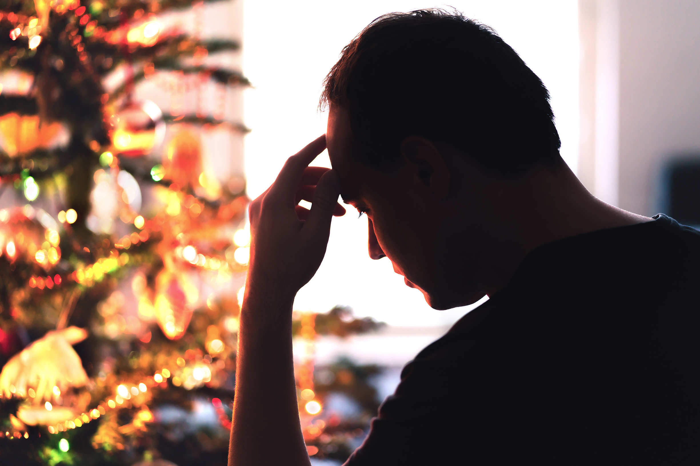 Un homme contrarié assis devant un sapin de Noël | Source : Getty Images