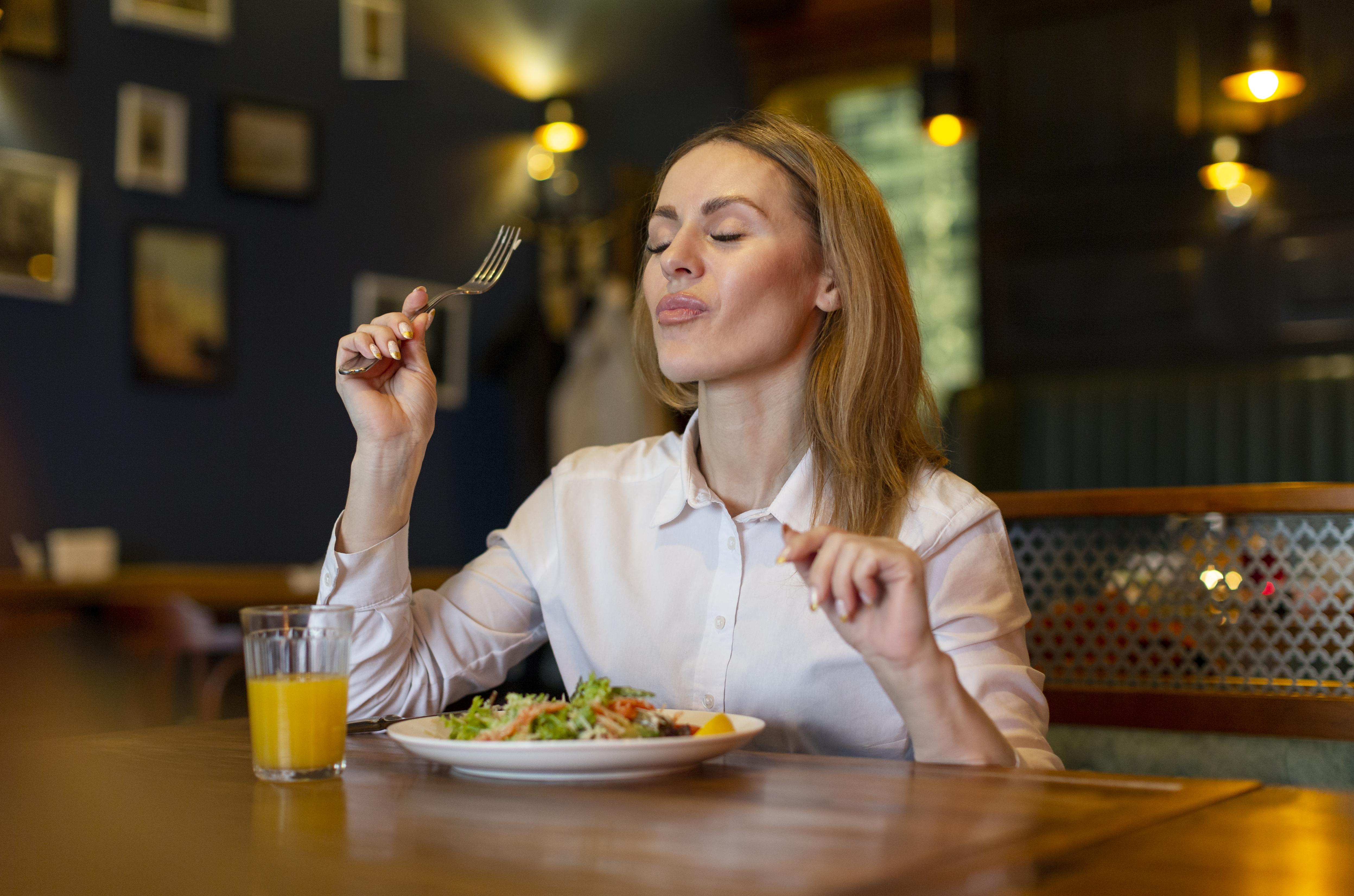 Une femme en train de déguster son repas | Source : Freepik