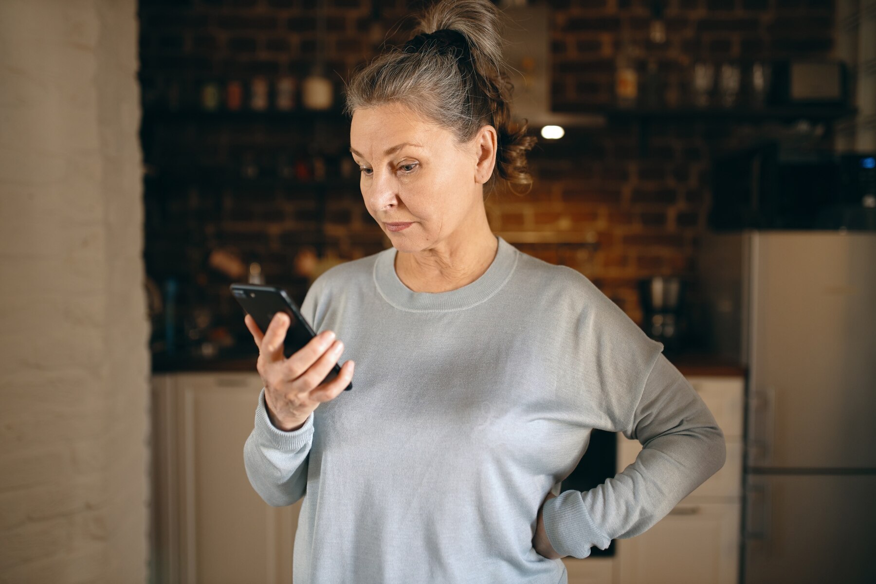 Une femme d'âge moyen en colère qui regarde son téléphone | Source : Freepik