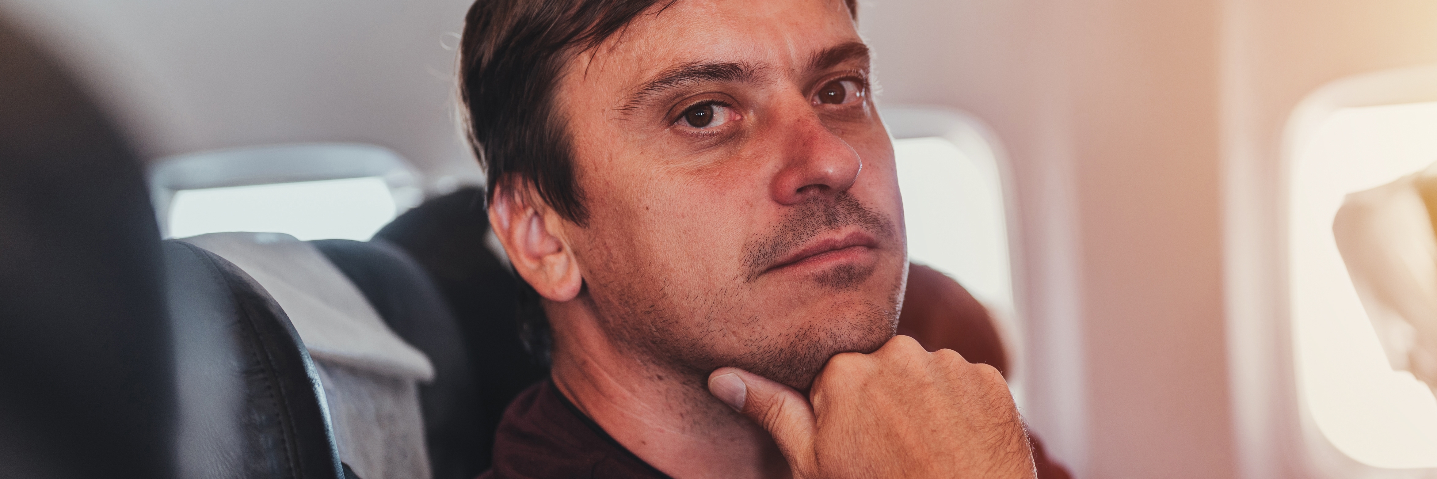 Homme réfléchi et coupable à l'intérieur d'un avion | Source : Shutterstock