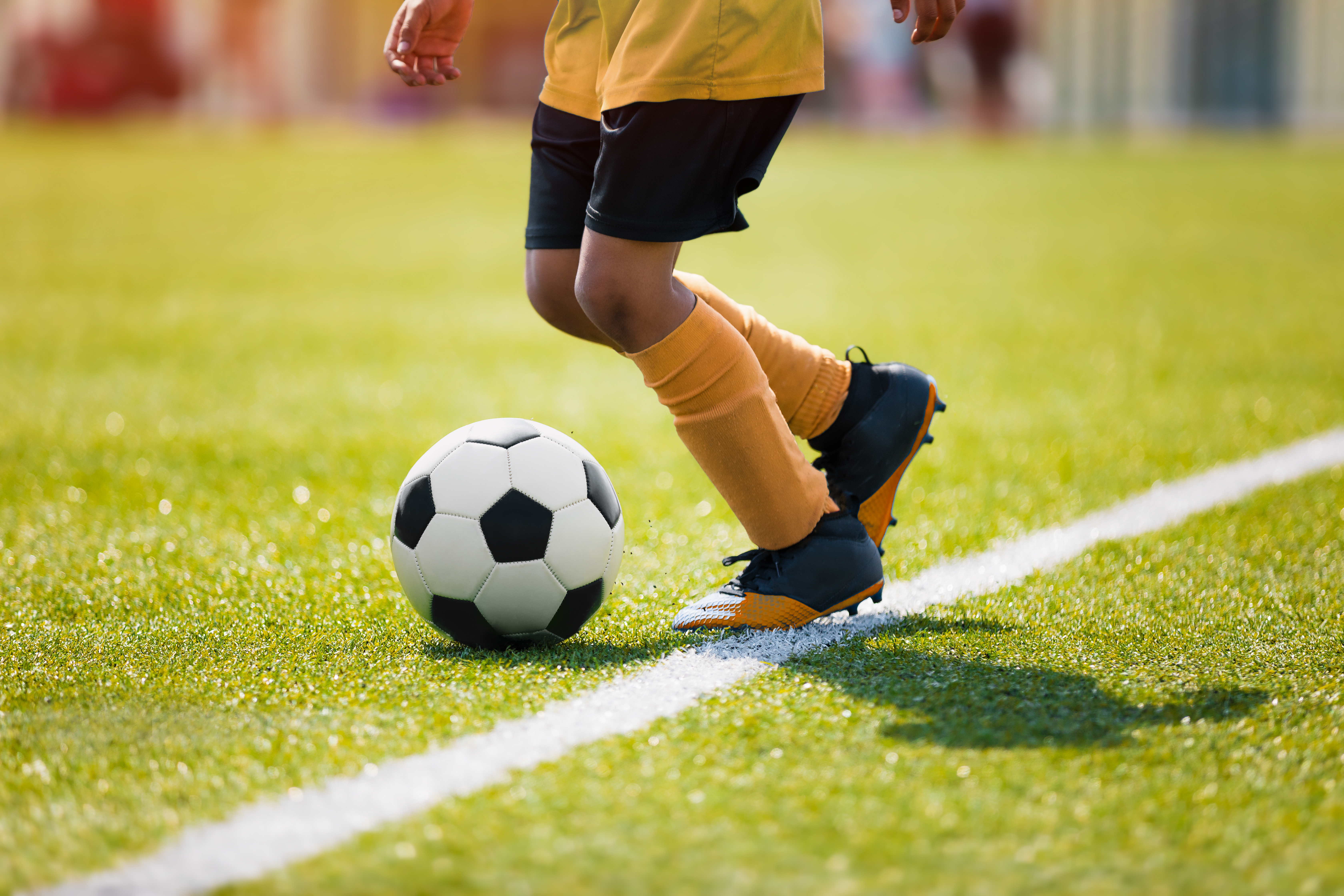 Un jeune enfant jouant au football sur un terrain | Source : Shutterstock