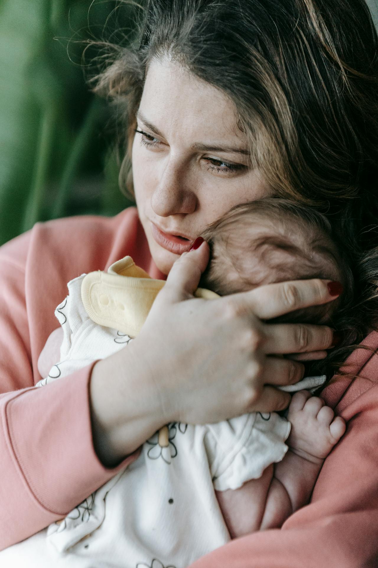 Une femme triste perdue dans ses pensées tout en serrant son bébé contre elle | Source : Pexels